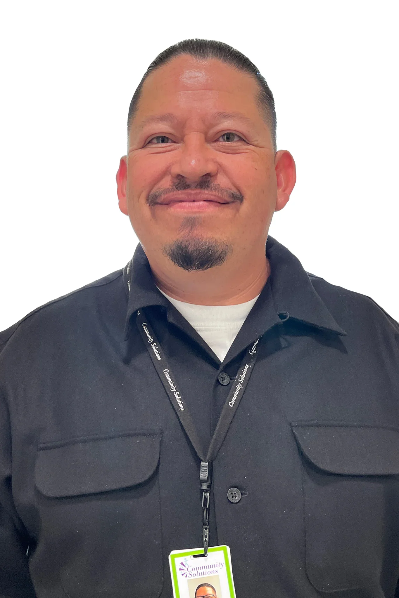 A smiling man wearing a black jacket with a lanyard and professional ID badge around his neck.