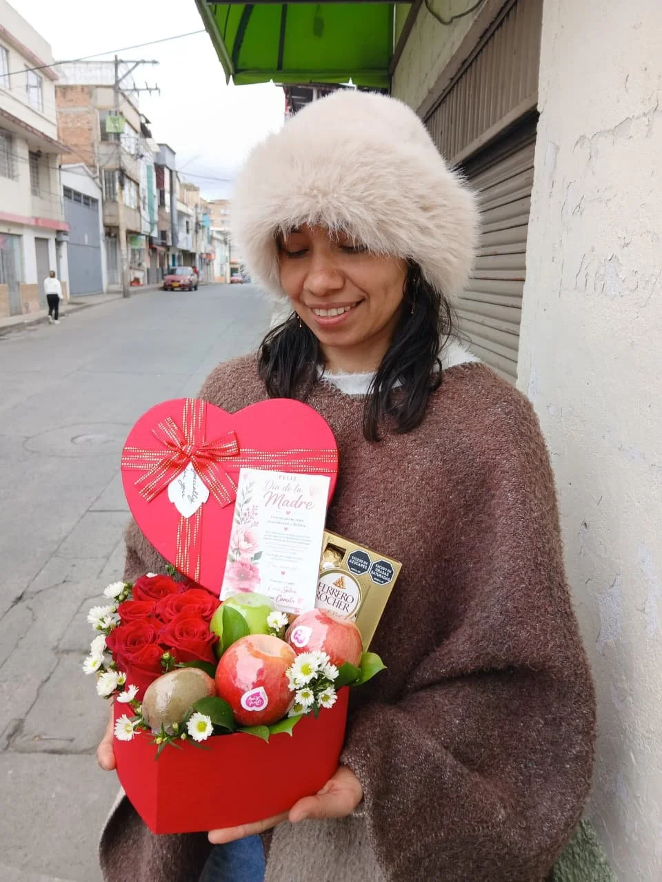 mujer feliz con caja corazon roja de 6 rosas rojas, 3 manzanas, un kiwui y una caja de 4 chocolates ferrero  .jpeg
