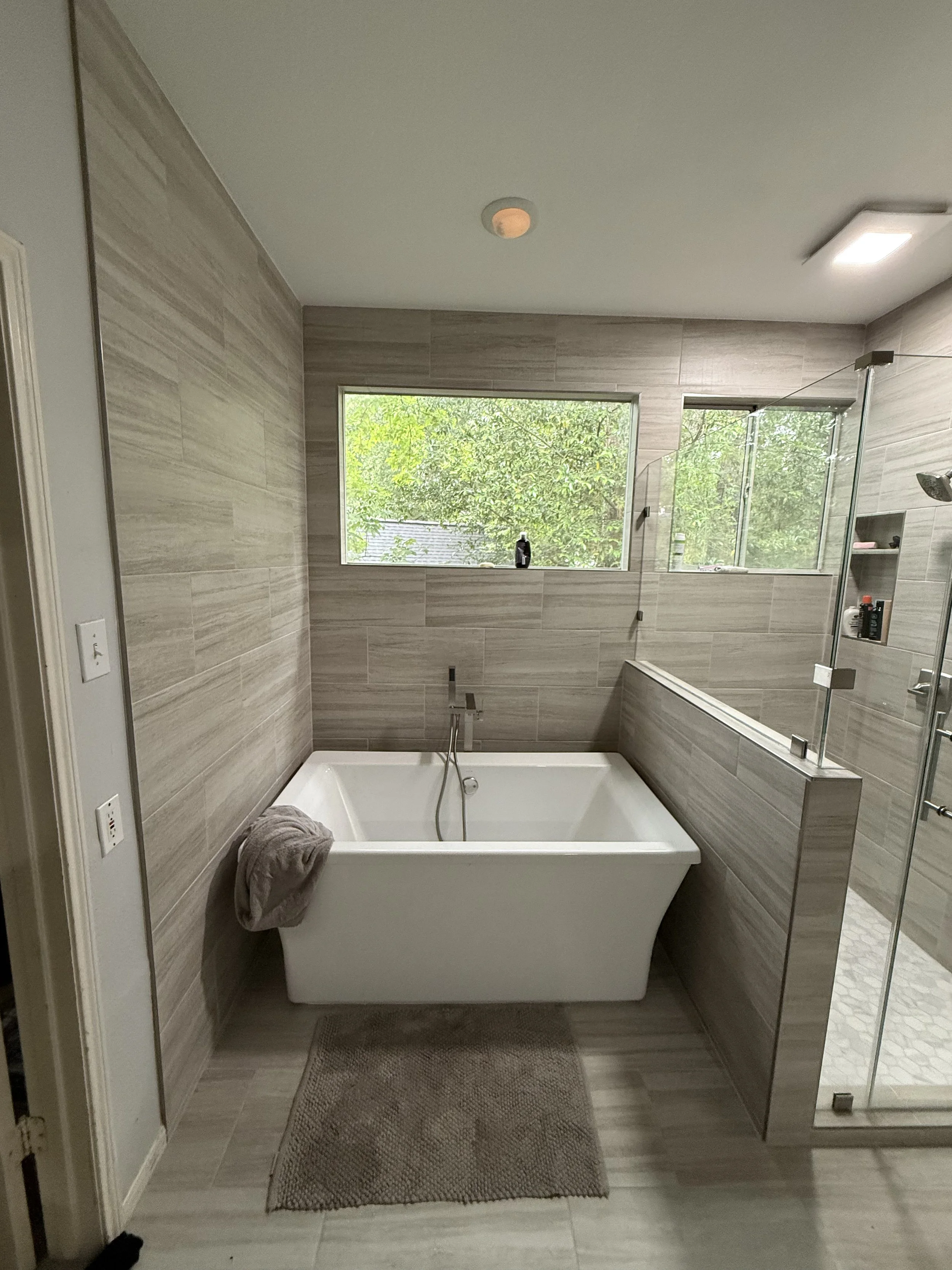 Bathroom tile installation with beige large format tile and glass shower enclosure in Conroe TX by Prestige Tile Solutions