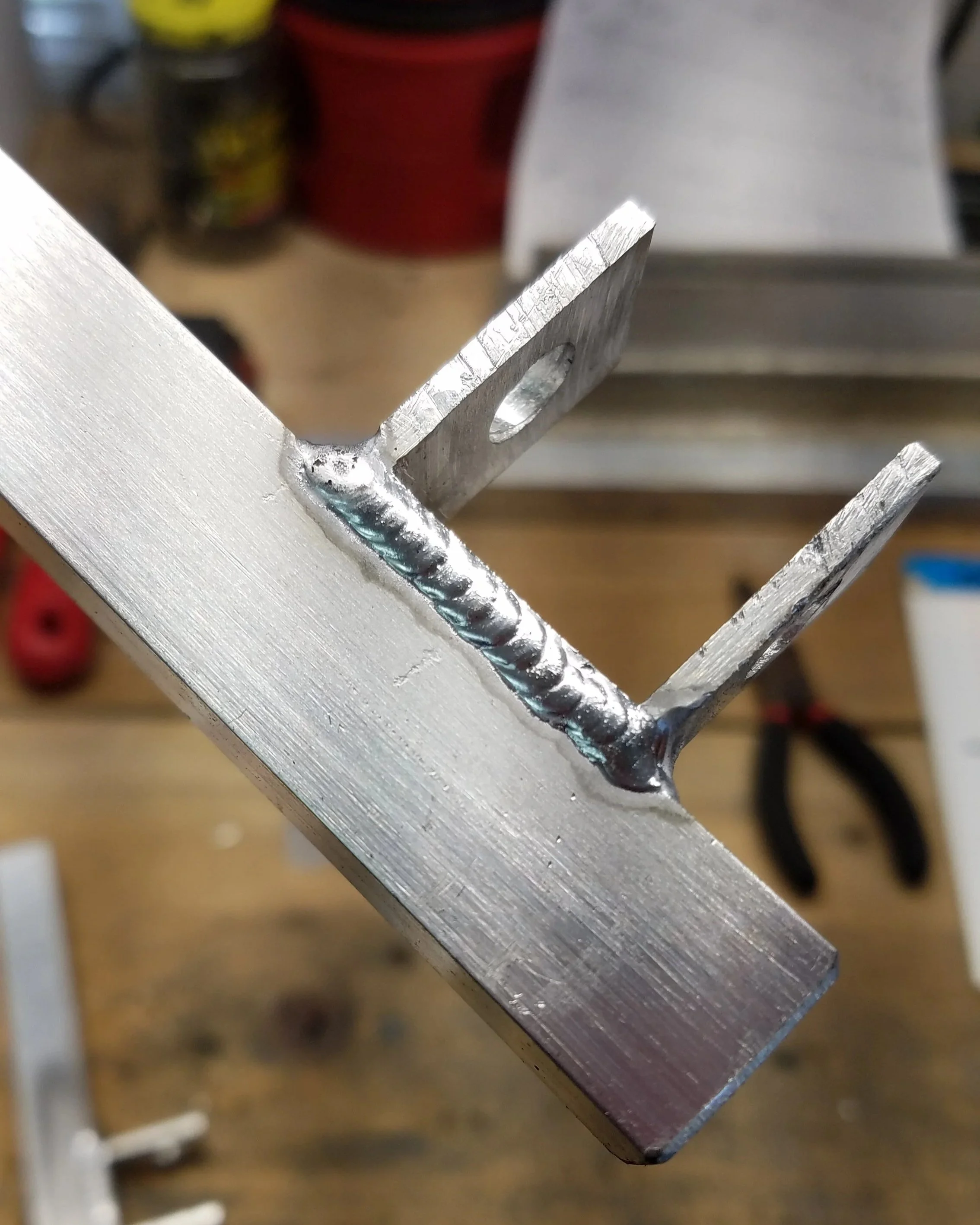 Close-up of a metal bracket with a welded joint, part of a larger metallic structure.