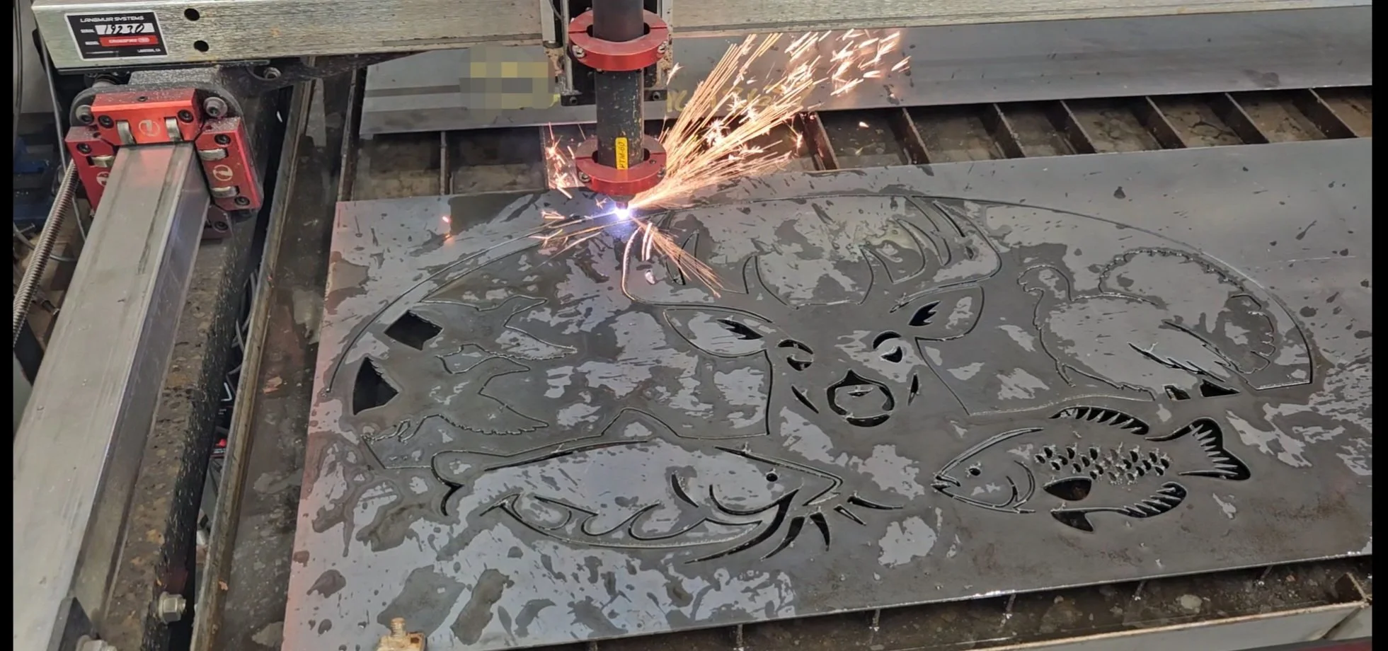 Metal sheet being cut with a plasma torch, revealing various fish and aquatic creatures in the design.
