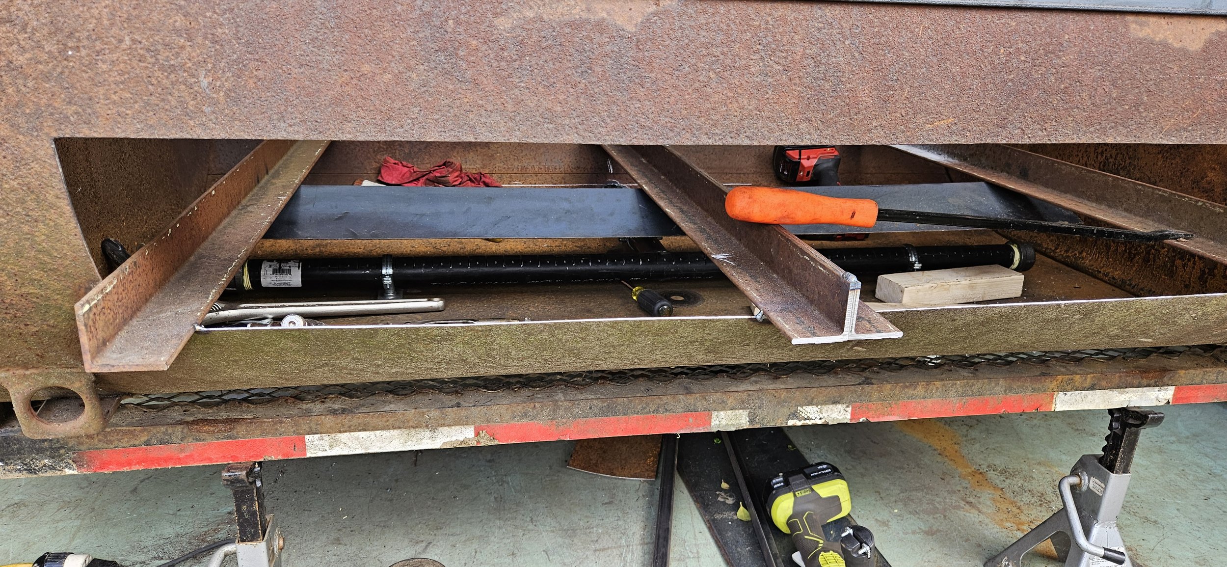 Construction workspace with steel beams, power tools, and hand tools on and around a metal work table.