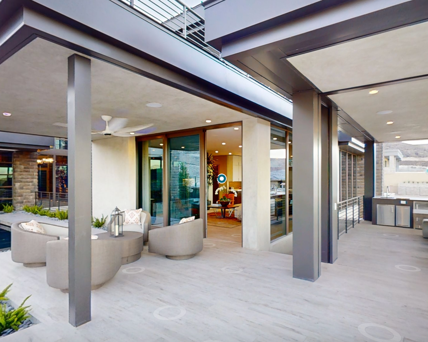 Modern outdoor patio with seating area, potted plants, and glass doors leading inside a house