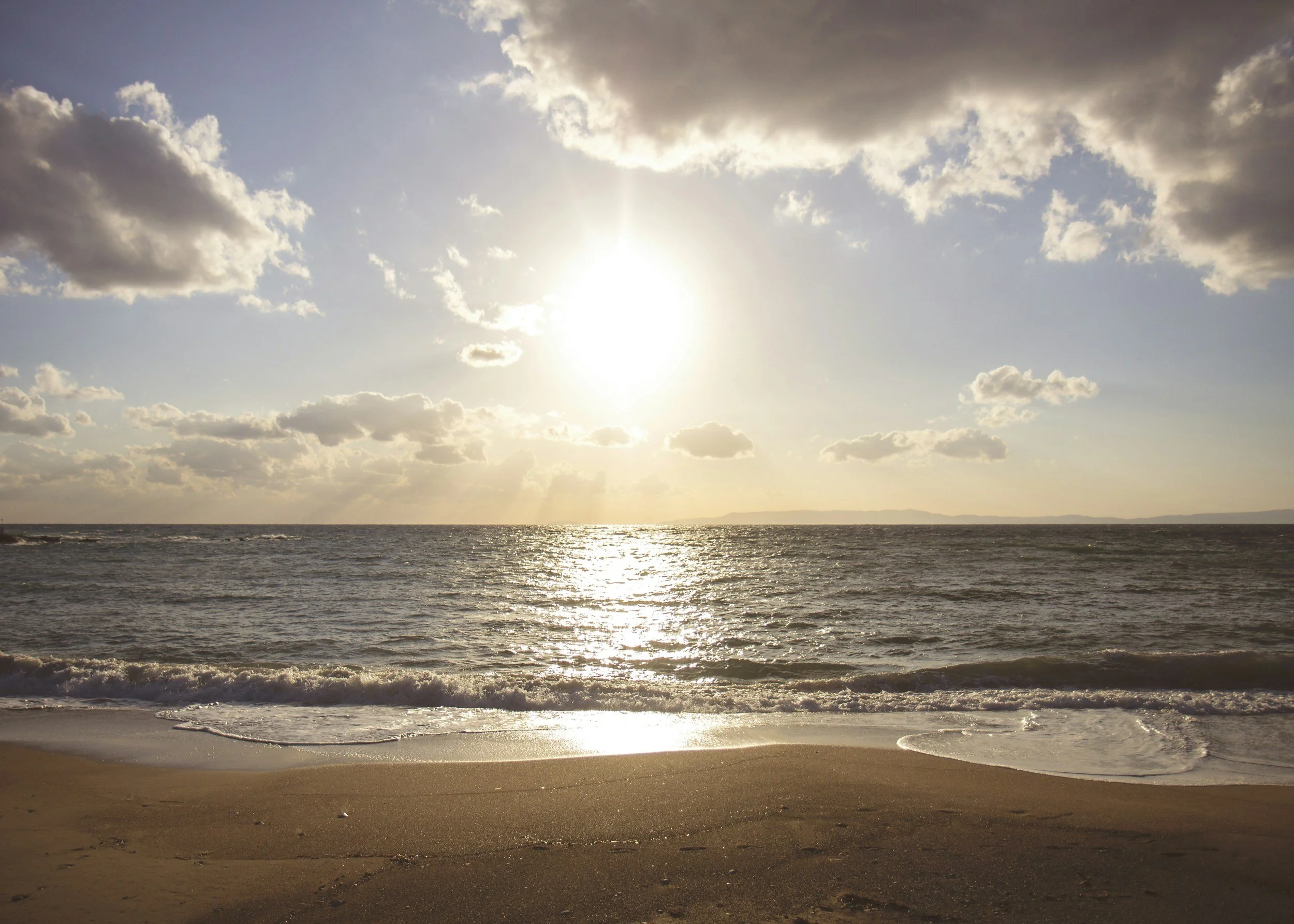 Sun setting over the ocean with clouds in the sky