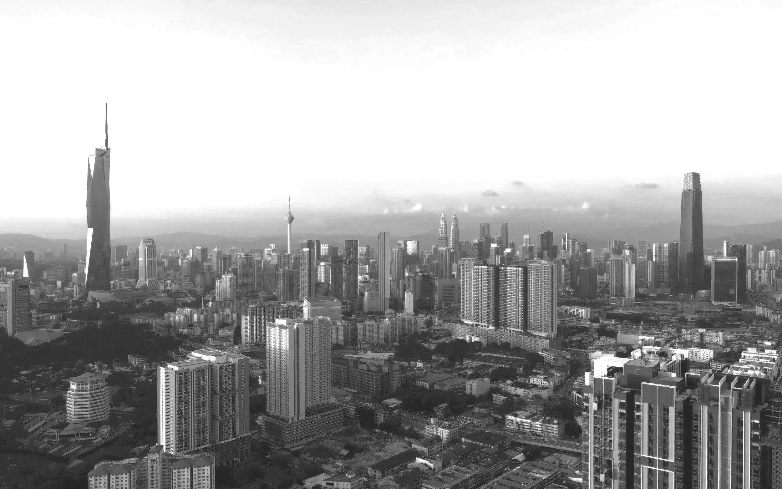 Vue de skyline en noir et blanc, avec la fameuse tour Petronas et plusieurs hauts immeubles autour.