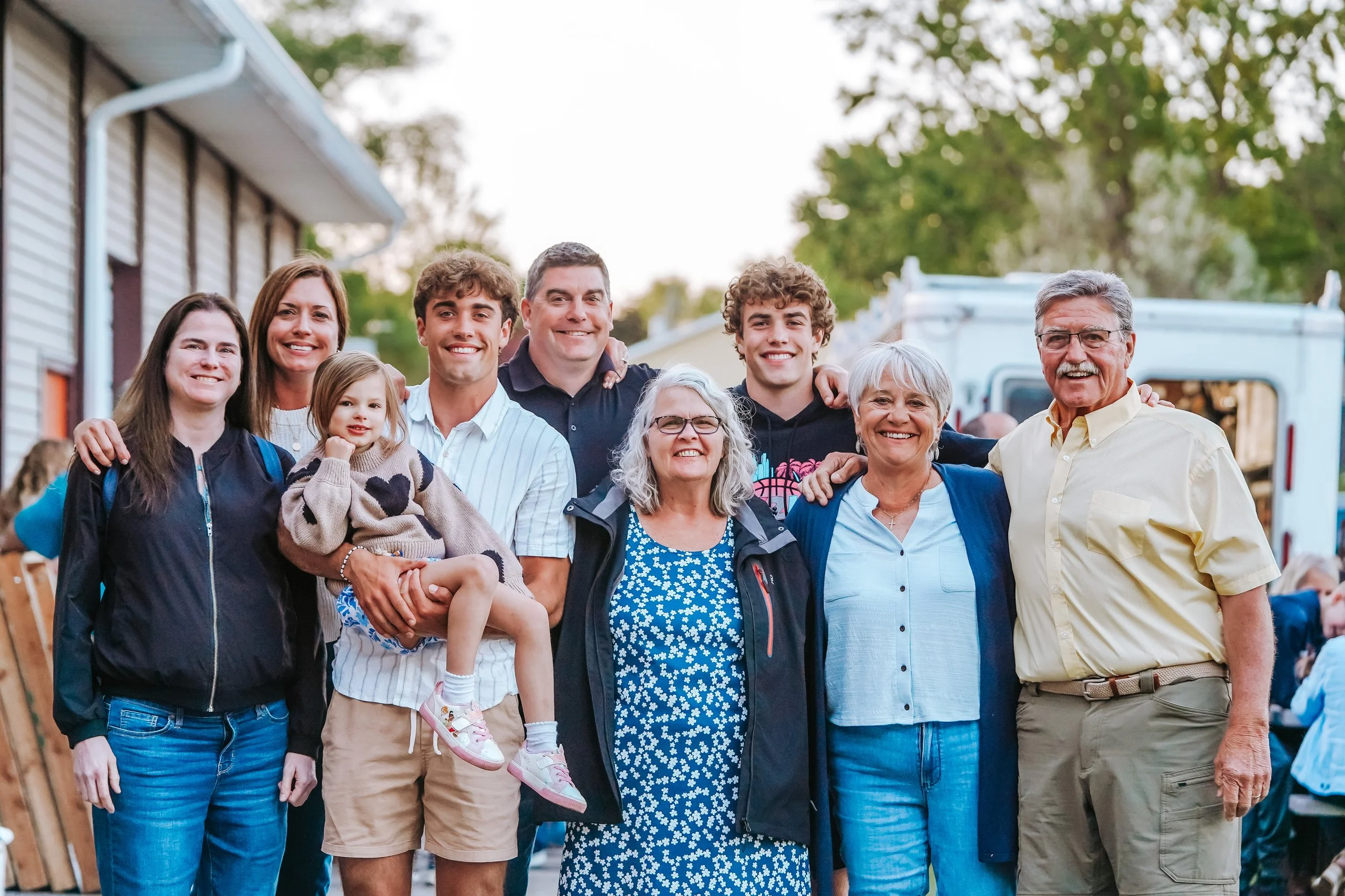 Group of diverse family members and friends smiling outdoors at a gathering.
