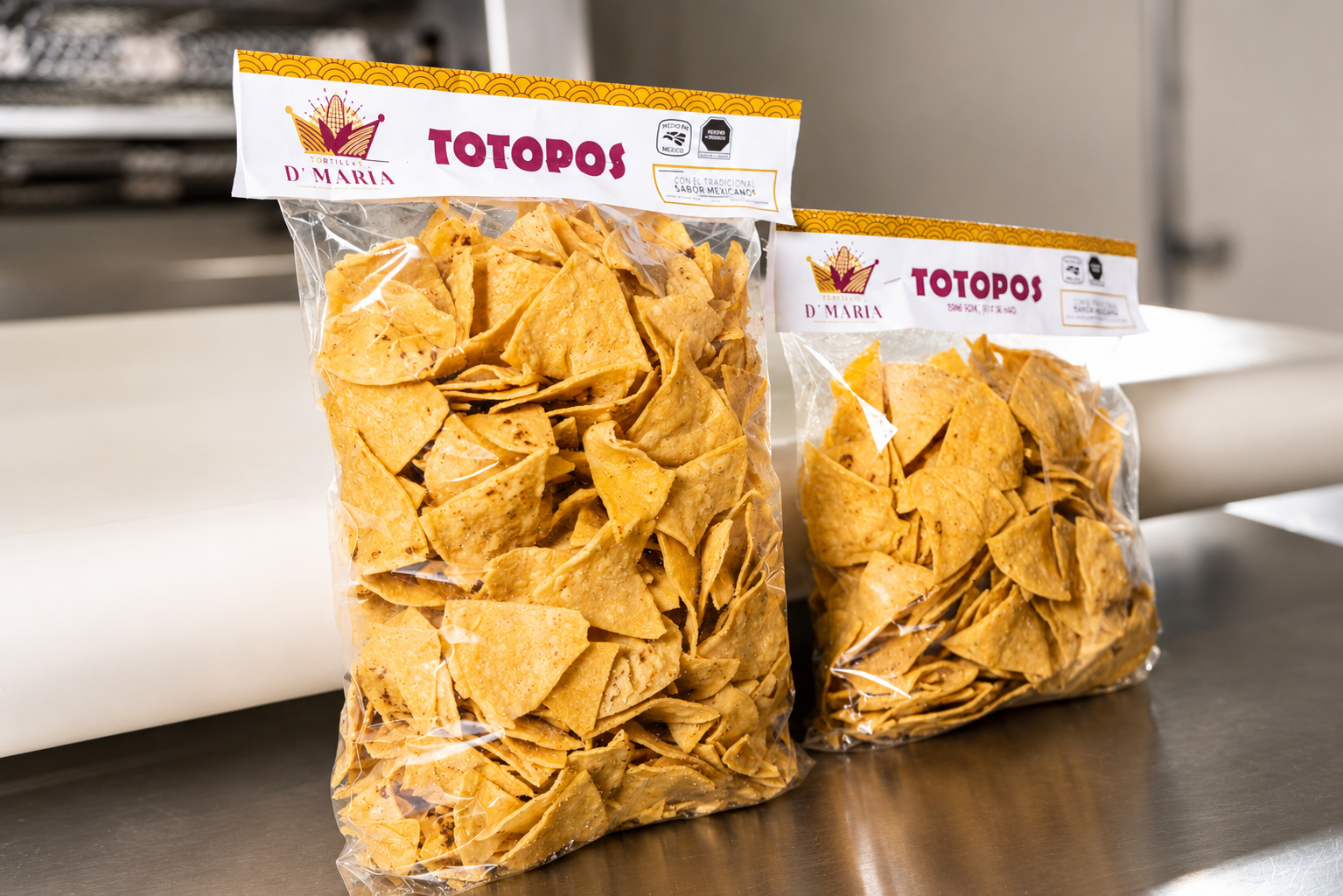 Two bags of tortilla chips on a stainless steel countertop with a white wall in the background.