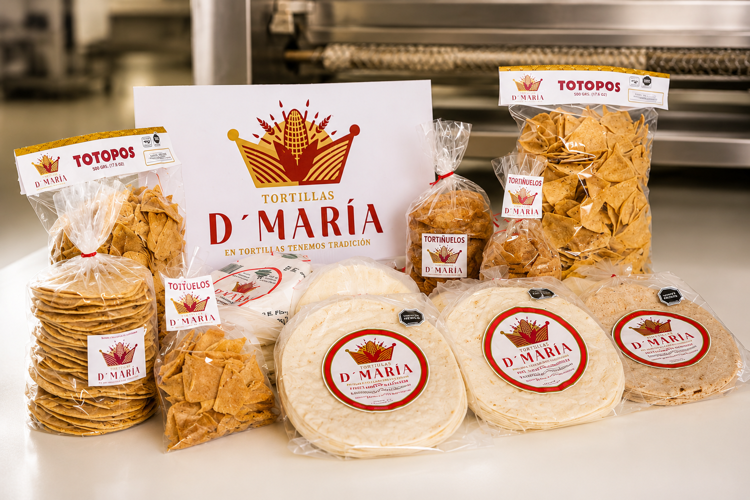 Various packaged tortillas and chips from Tortillas D'María displayed on a table with a white sign featuring a crown and wheat logo.