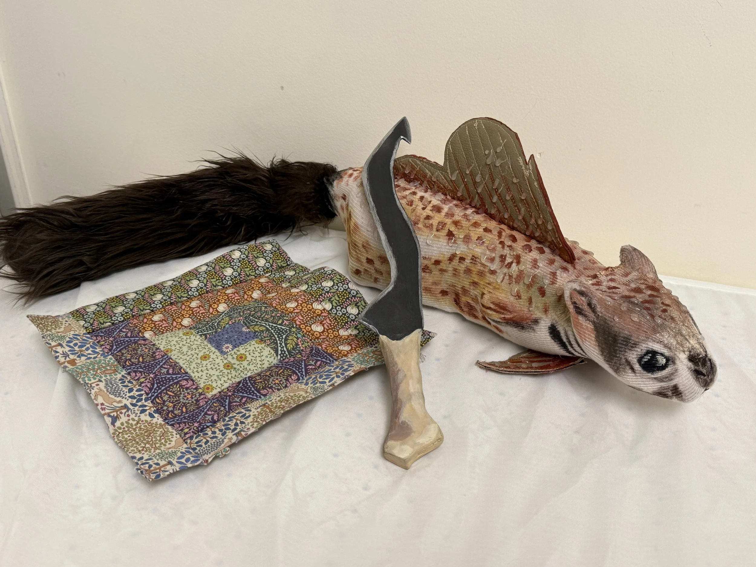 3 props: knife, quilt piecing, squish (squirrel fish)