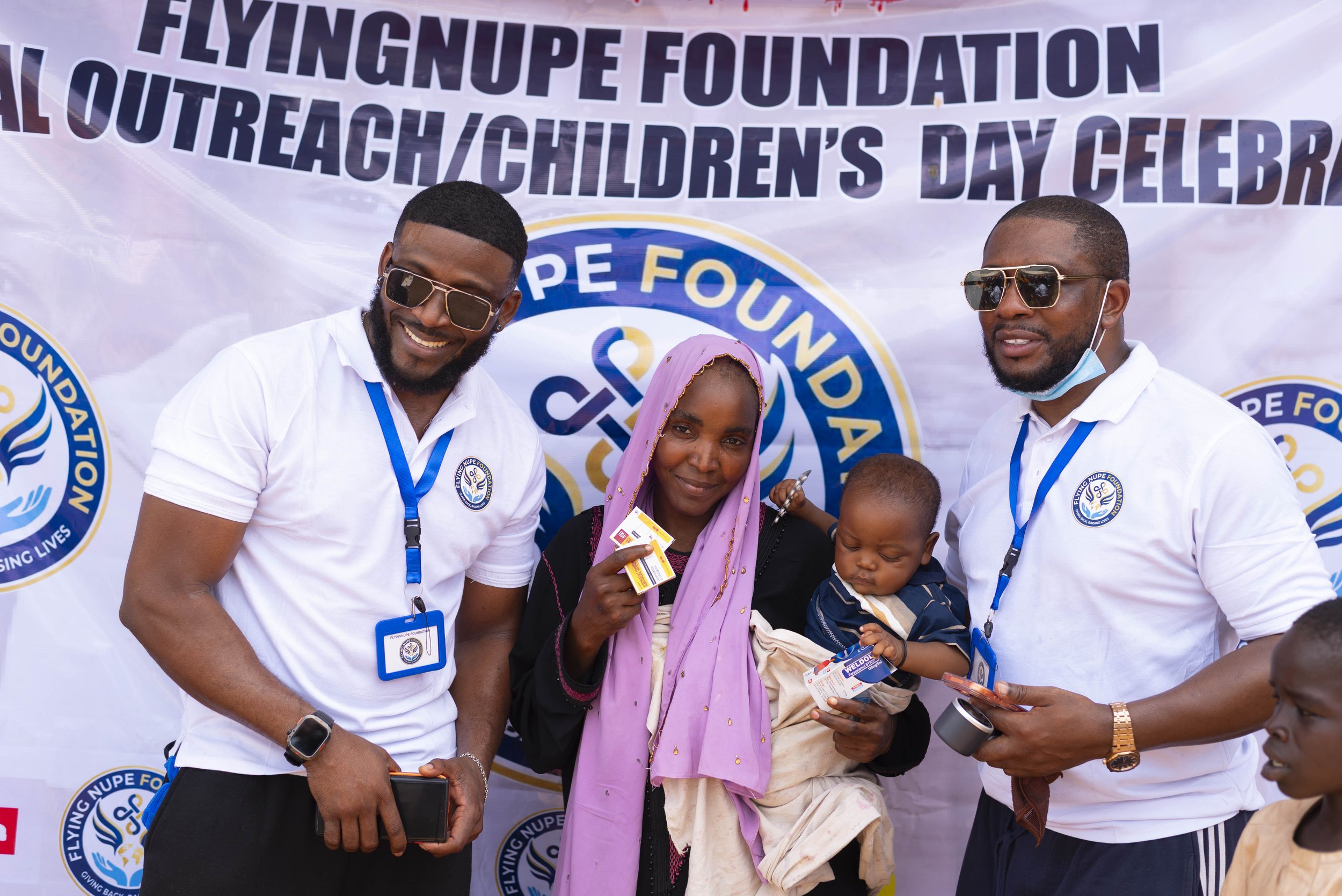 Group of people standing in front of a banner at a celebration event, smiling and holding tickets.