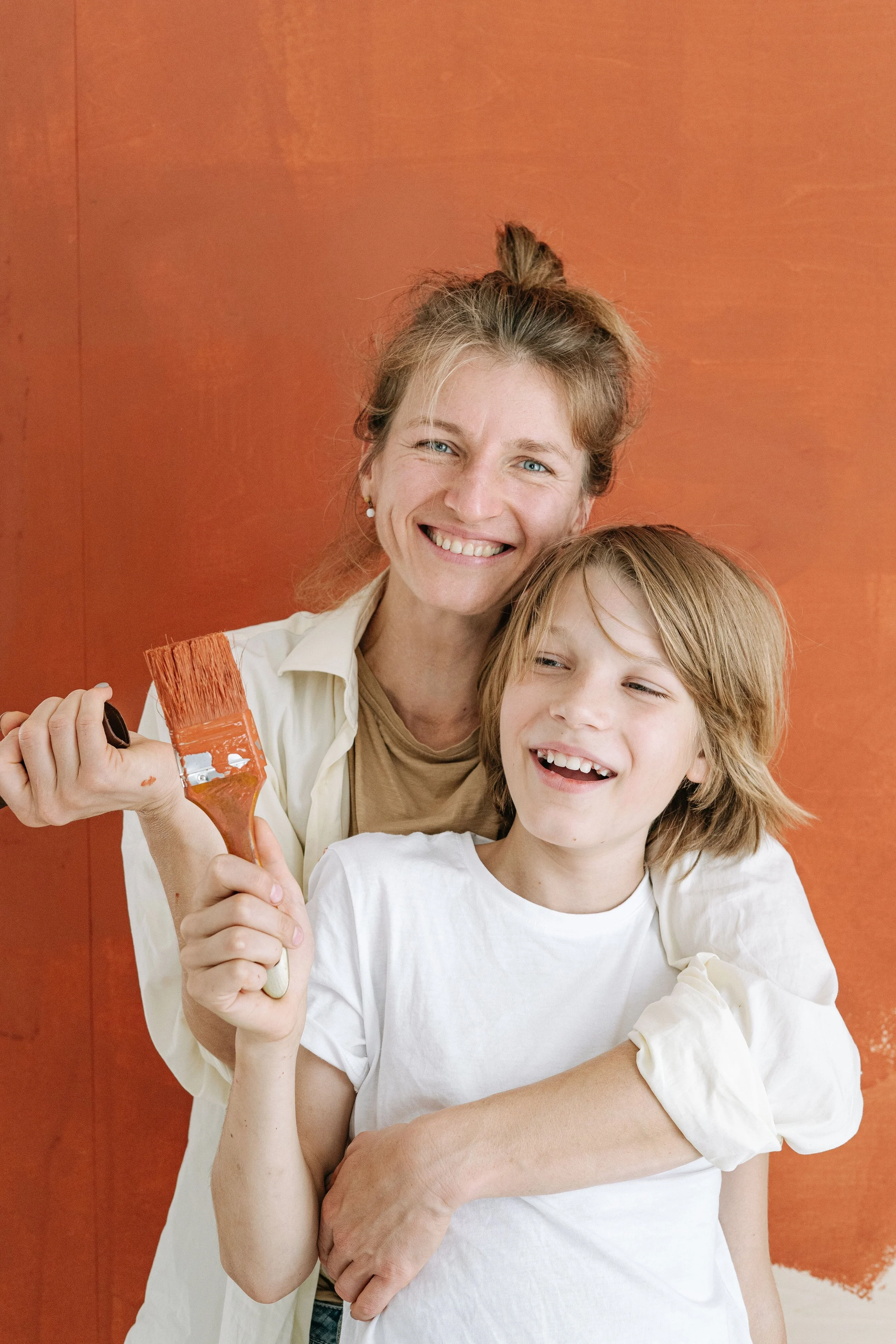 mother and son painting an orange wall
