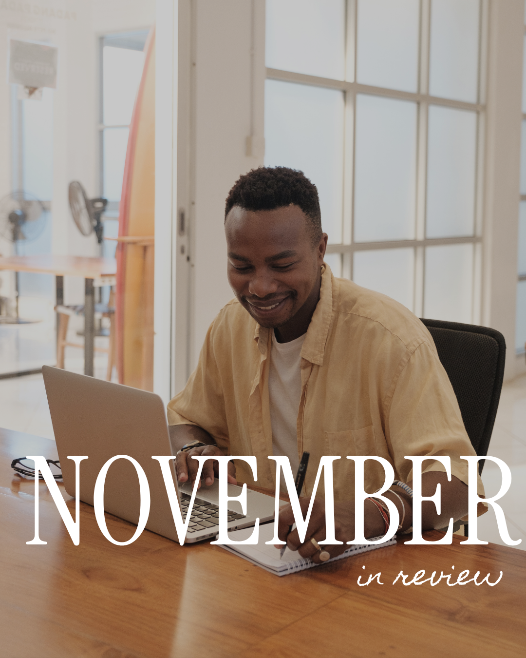 Man working on a laptop and writing in a notebook at a wooden desk, with “November in review” text overlay.