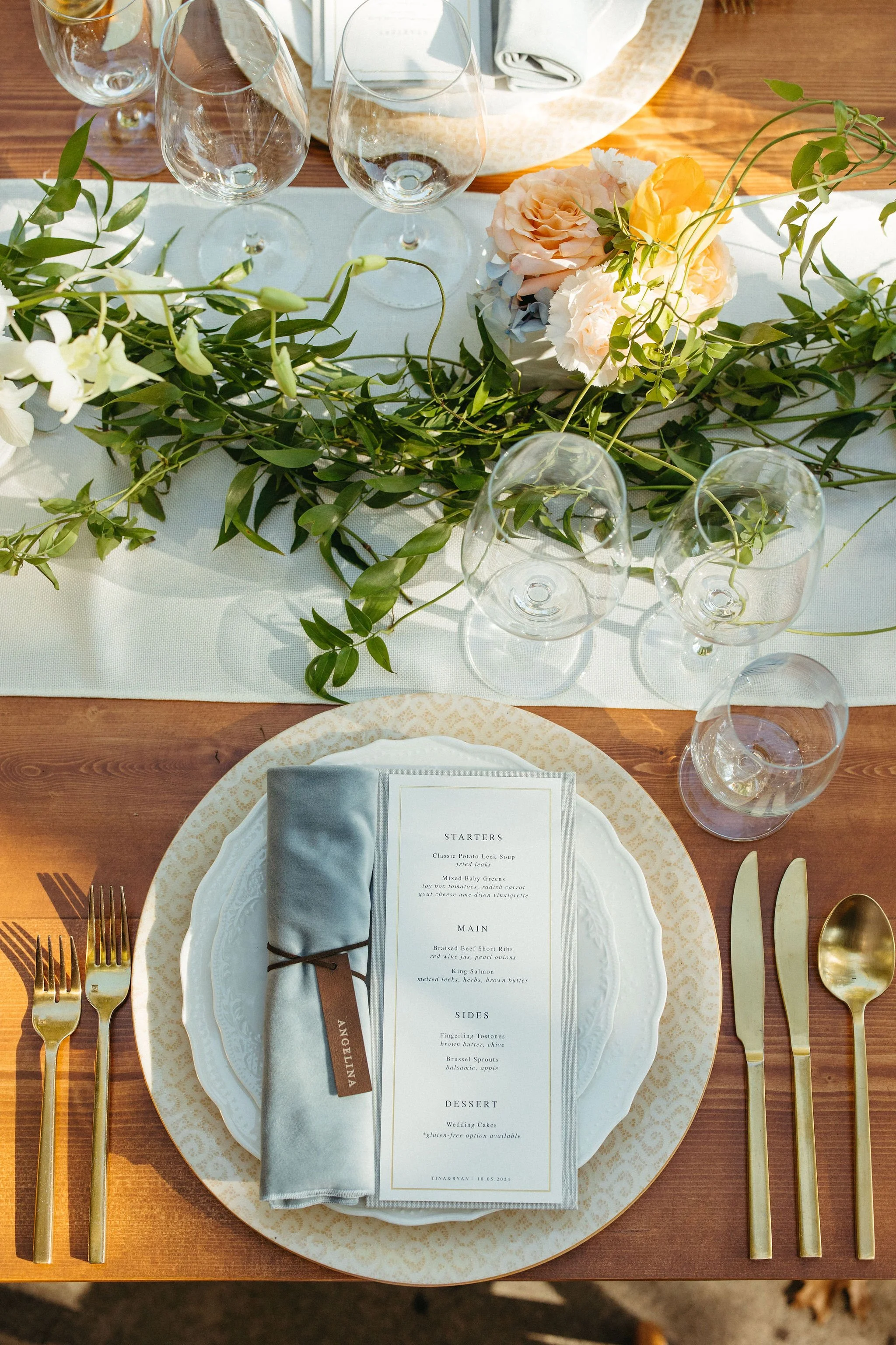 Place setting with a menu card and floral centerpiece at a wedding styled by Events by GS.