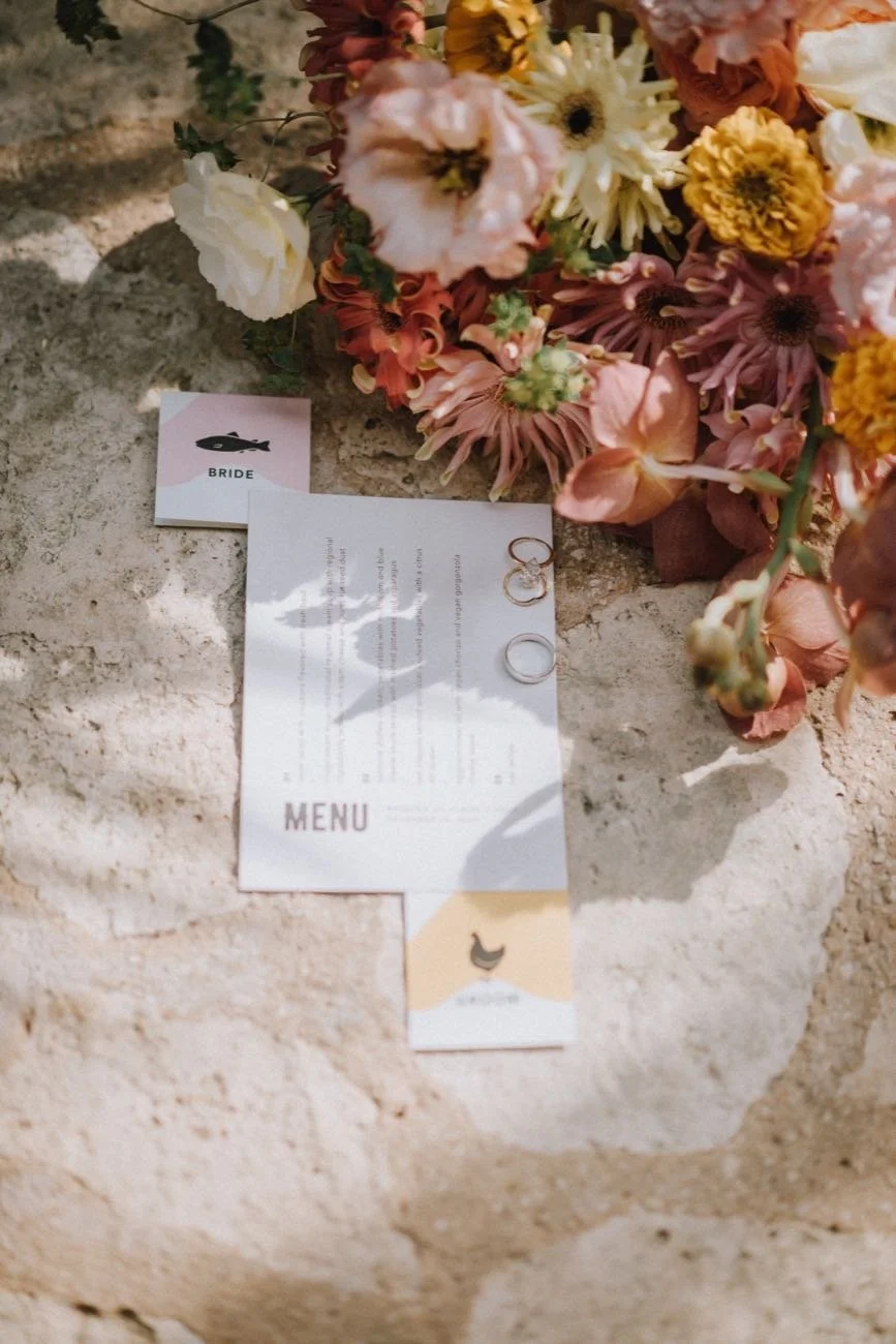 Wedding rings on a menu card with a bouquet at a destination wedding by Events by GS.