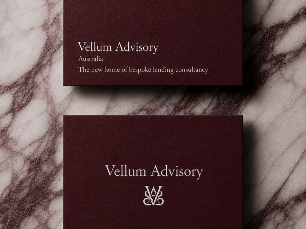 Marble surface with two dark red business cards, one says "Vellum Advisory Australia The new home of bespoke lending consultancy" and the other displays the Vellum Advisory logo.