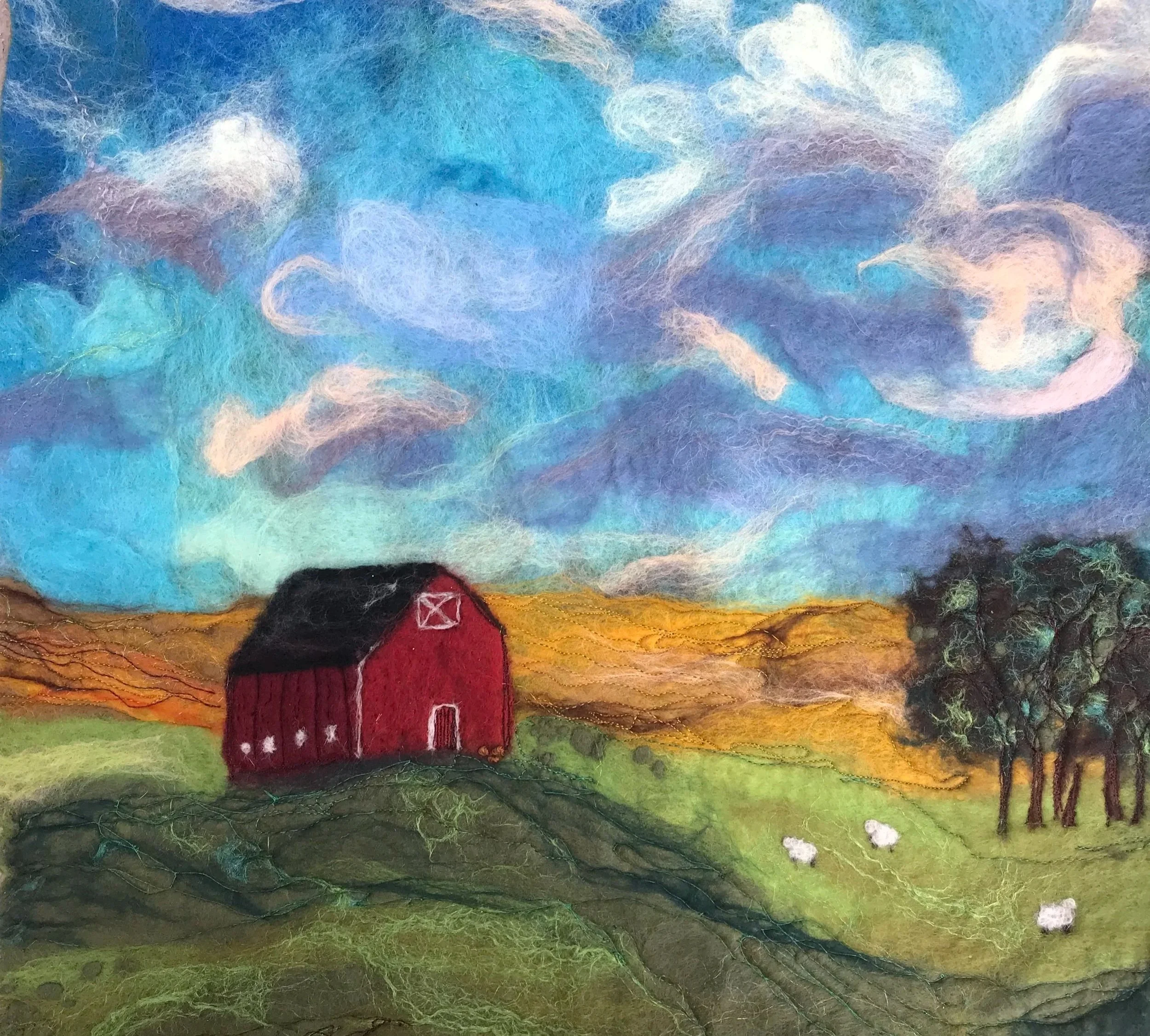 Colored felt landscape art with a small house, trees, a sky with clouds, and grass.