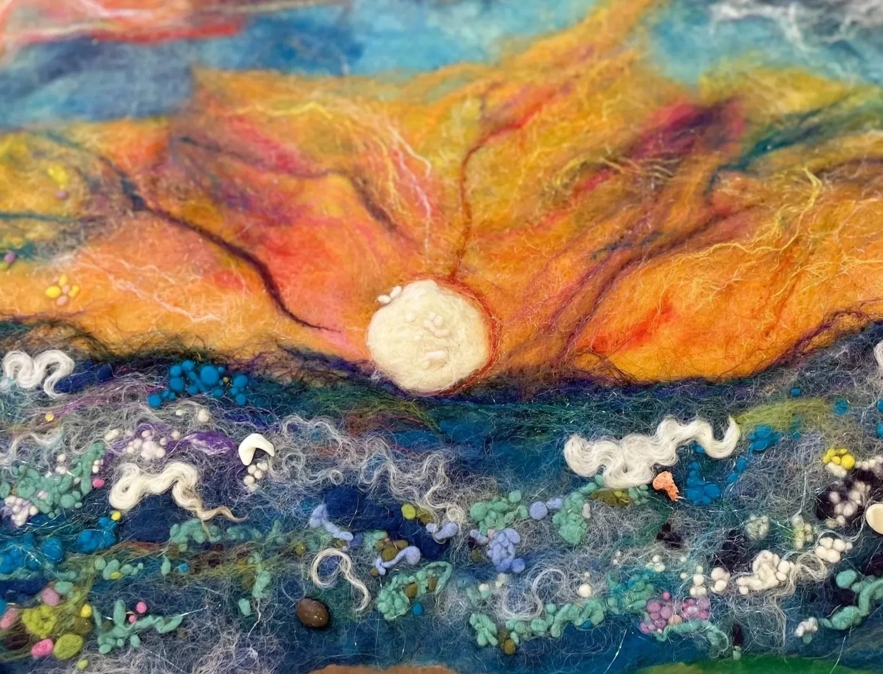 Abstract textured artwork with colorful felt, yarn, beads, and mixed media elements creating a vibrant, organic scene.