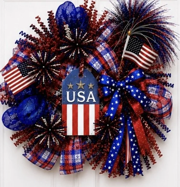 Fourth of July patriotic wreath with red, white, and blue decorations, including flags, ribbons, and fireworks-themed ornaments.