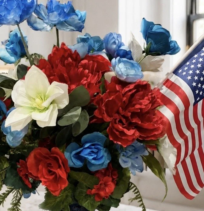 A bouquet of red, white, and blue artificial flowers with an American flag attached.