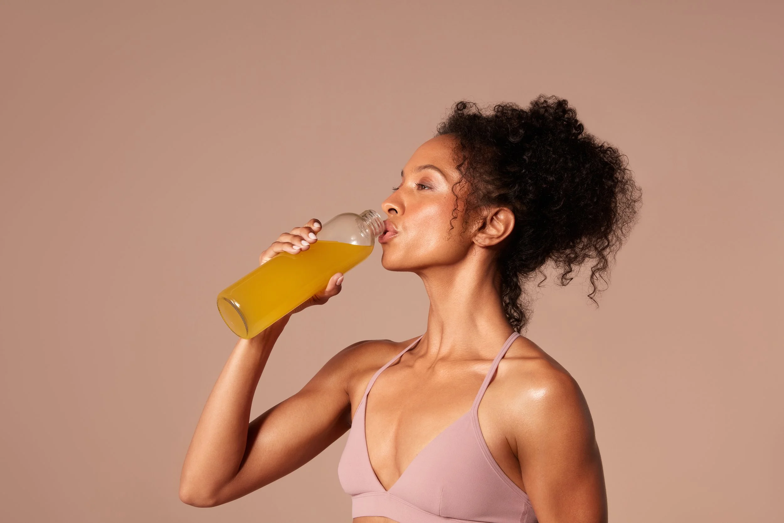 Woman drinking Hydroxycut Ultra Shred Drink Mix from a clear sports water bottle