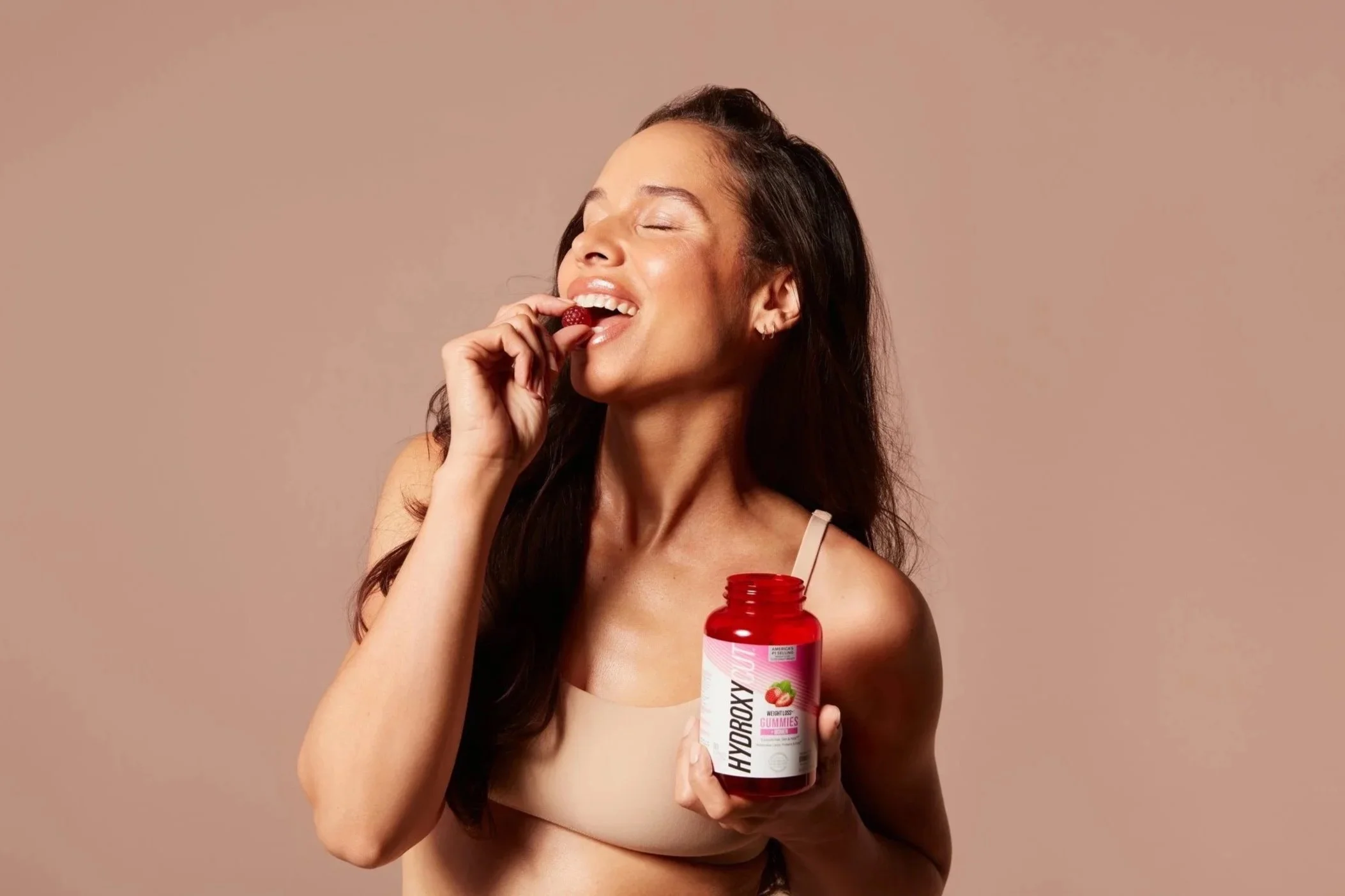 Woman biting a hydroxycut women's gummy