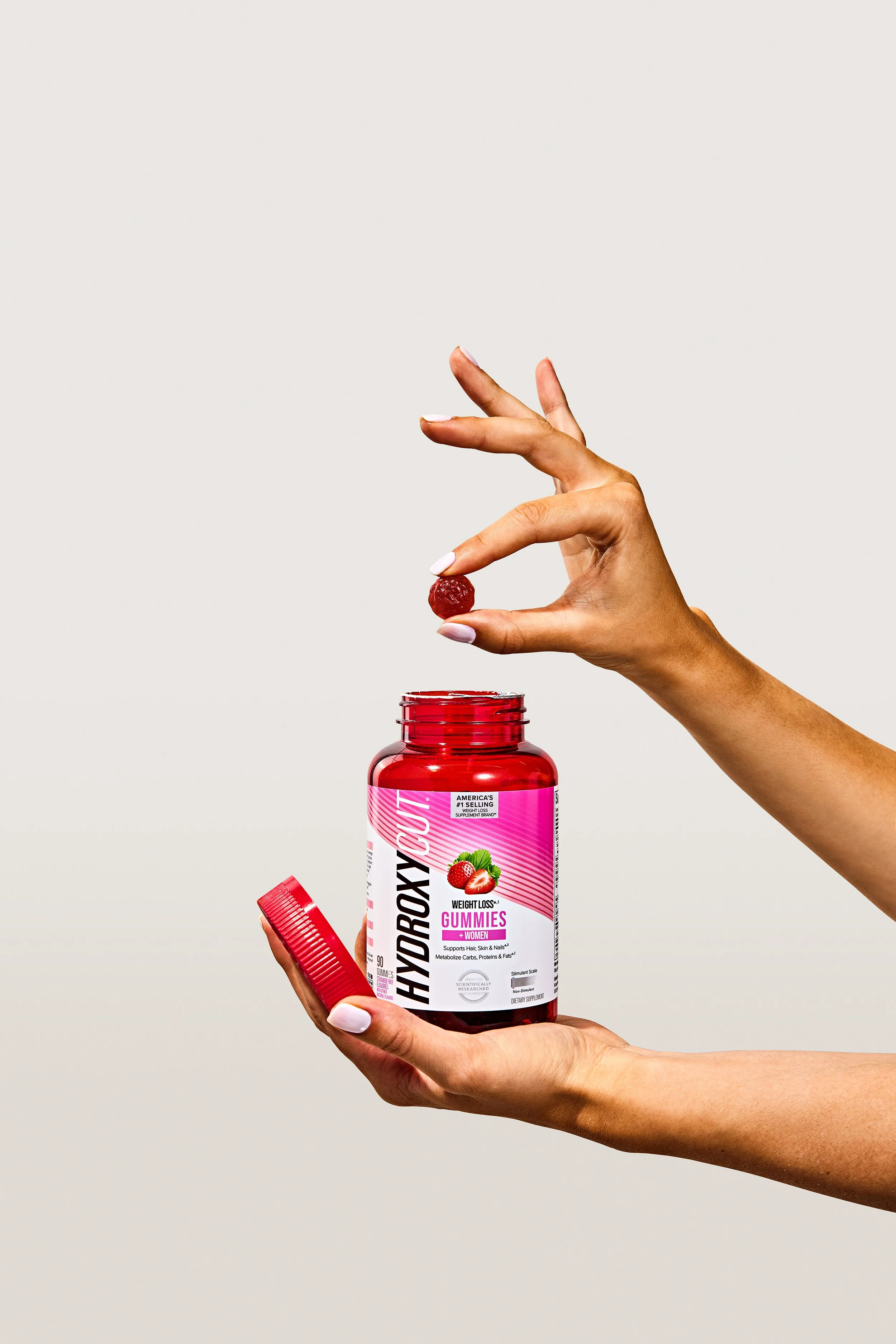 Hydroxycut Women's Gummies held in one hadn't with one gummy in between fingers