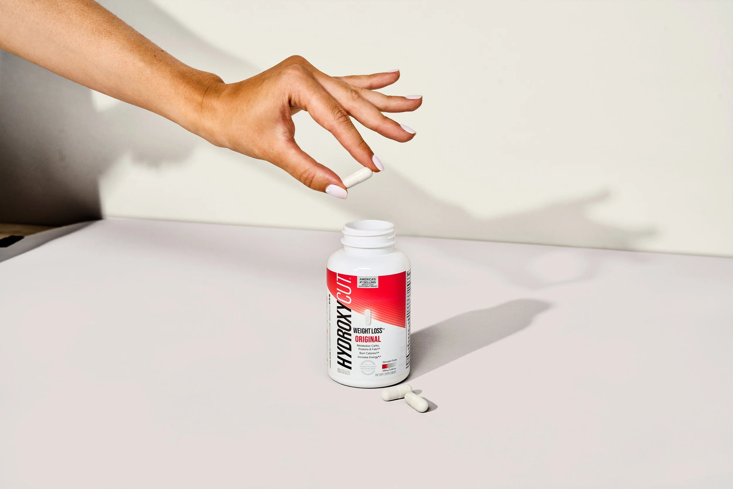 Hydroxycut Original Pills with one pill in fingers