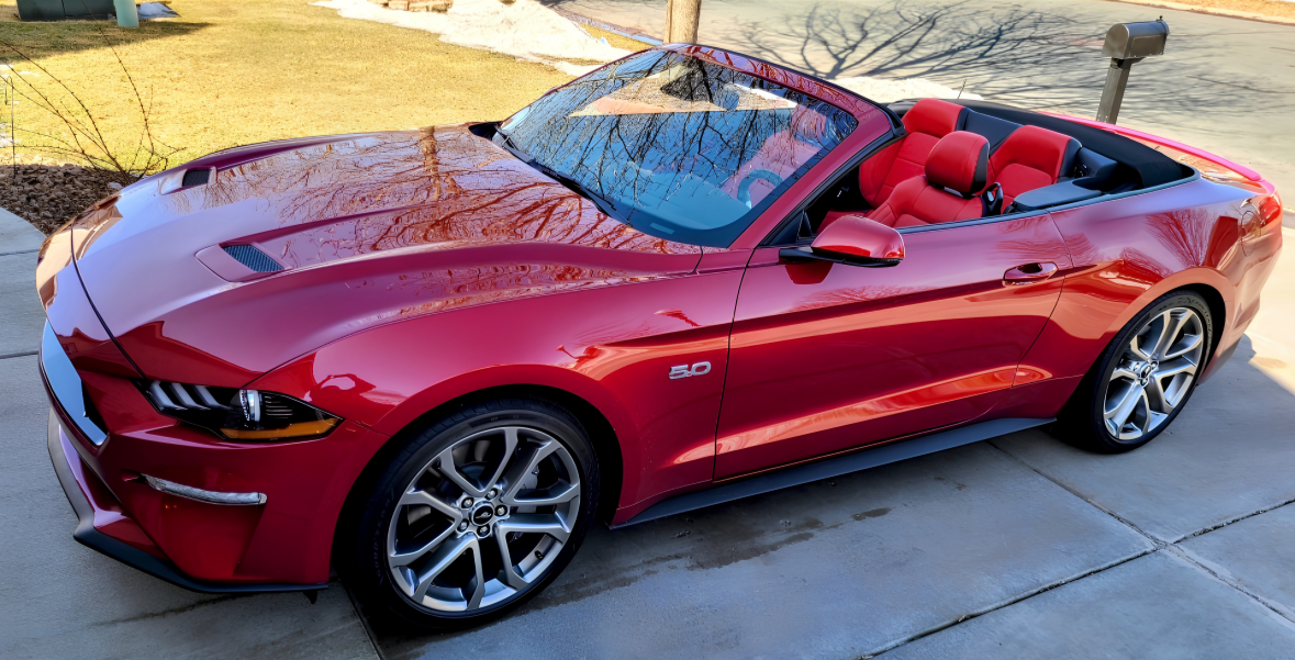 Red convertible car parked on driveway with red interior seats.
