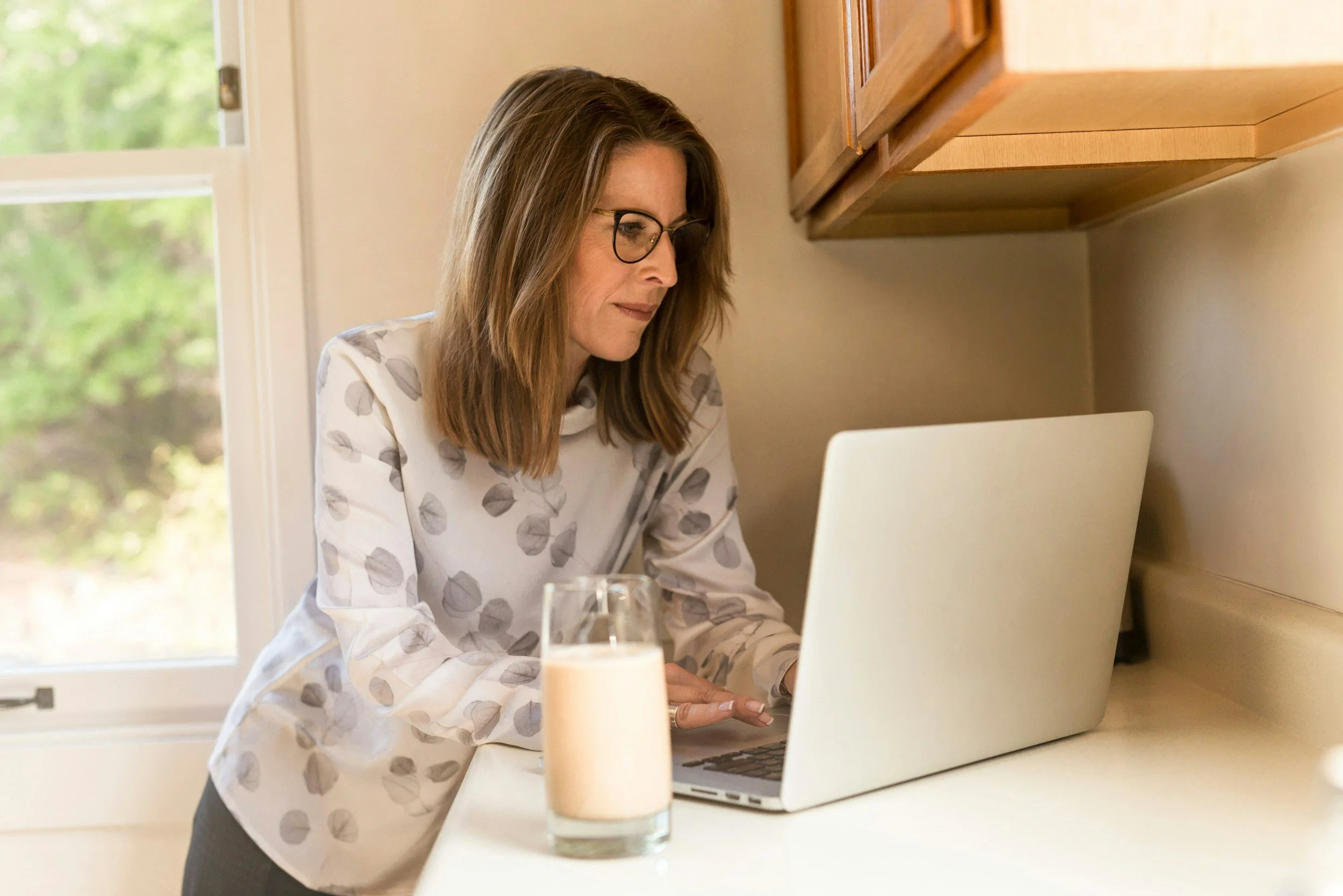 Woman working on a laptop at a kitchen counter