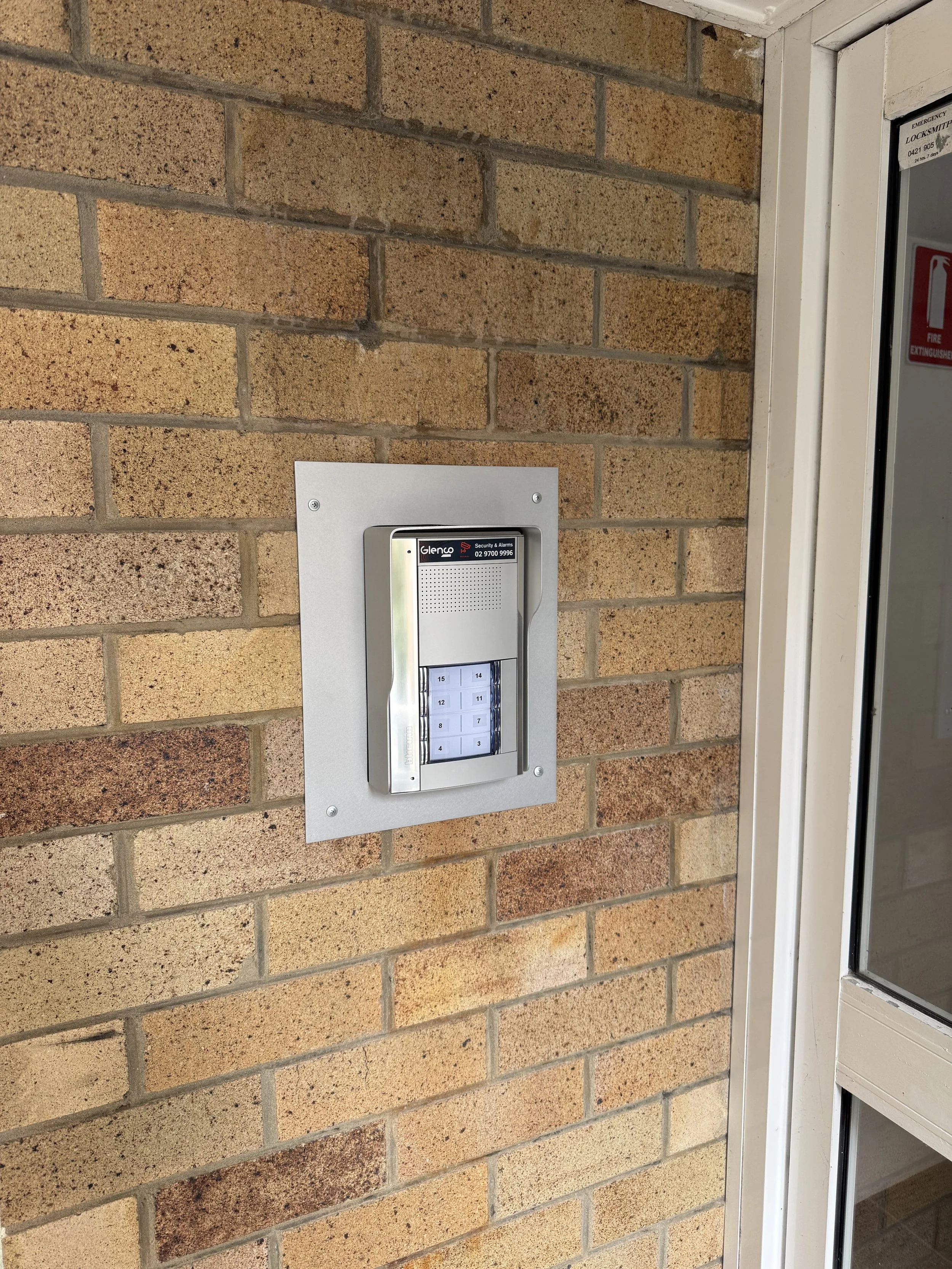 A brick wall with an intercom or security keypad mounted on it
