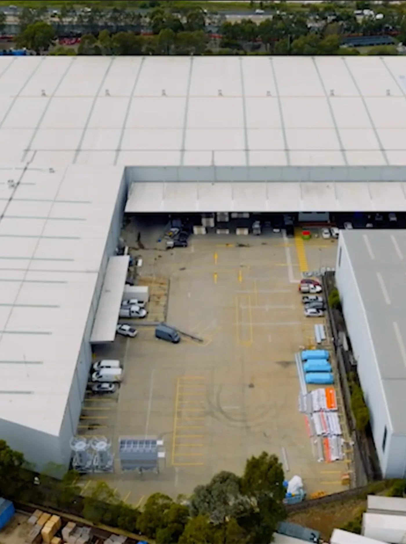 Aerial view of a large commercial building with a white roof and parking lot.