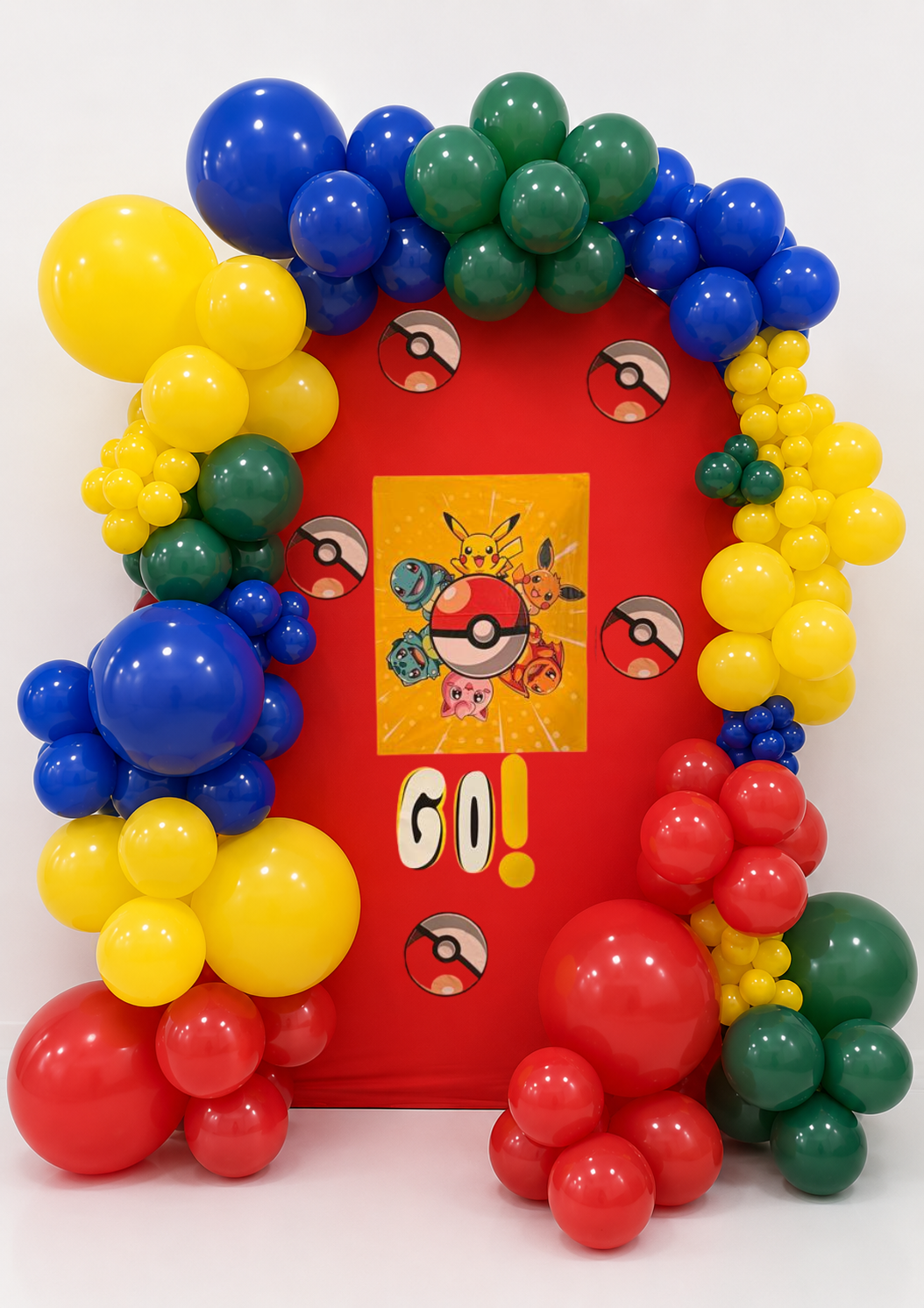 Colorful Pokémon-themed balloon decoration with a red backdrop. There are various sizes of balloons in blue, yellow, green, and red, arranged around a Pokémon poster with Pikachu, Eevee, and other Pokémon. The poster features Pokémon and Poké Balls, with the word "GO!" in large letters.