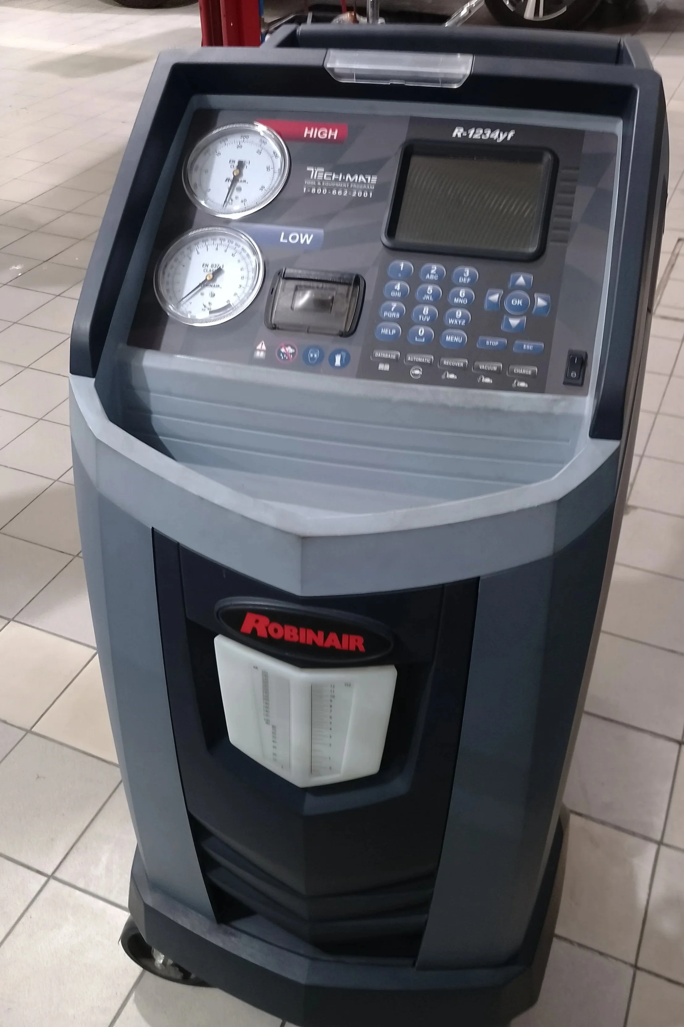 Aparato de reparación de llantas marca Robinair con dos manómetros, una pantalla digital y botones en un entorno de taller.