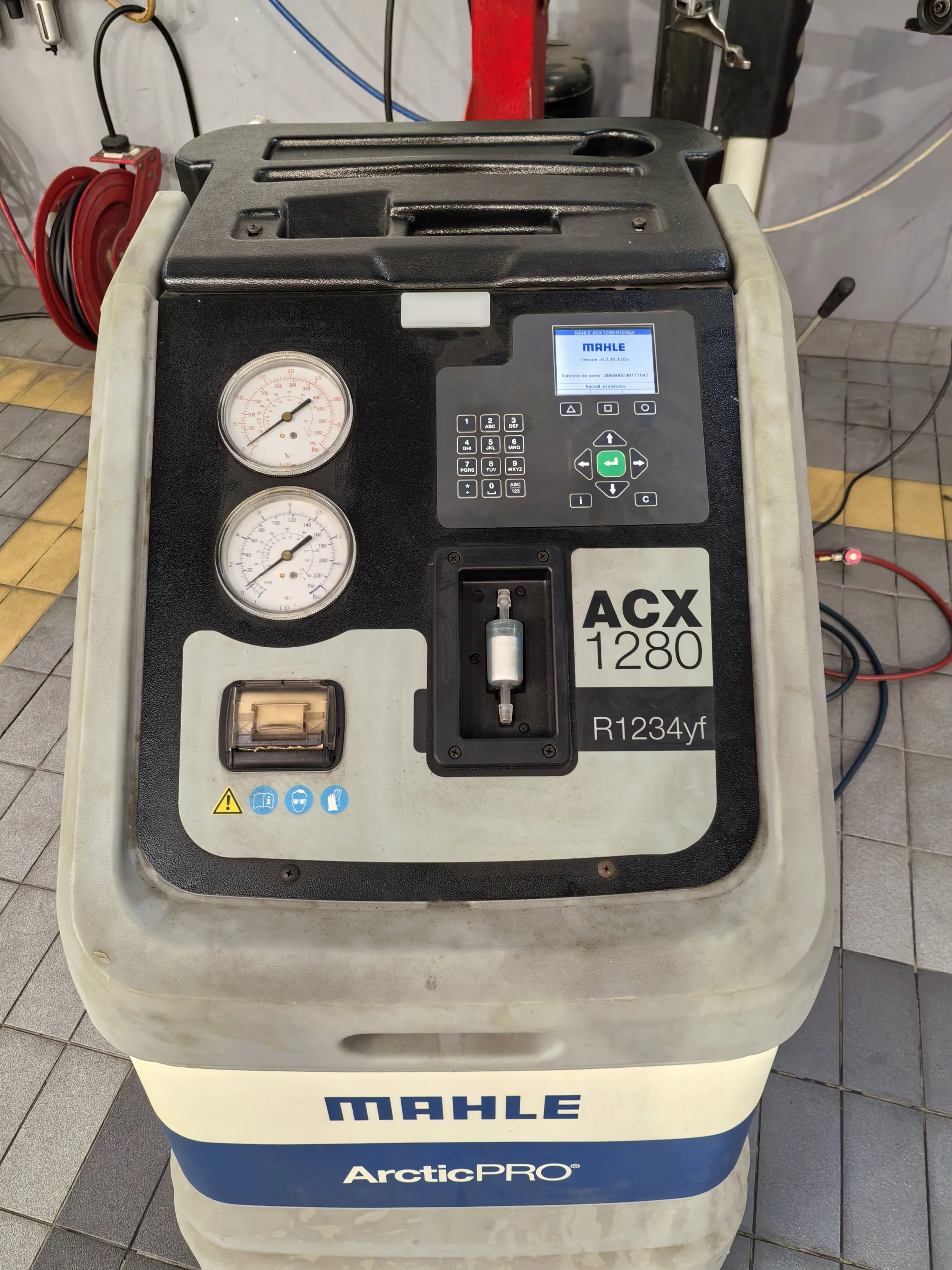 Unidad de refrigeración de prueba Mahle ArcticPRO marca ACX 1280 con manómetros, pantalla digital y controles en un entorno de taller.