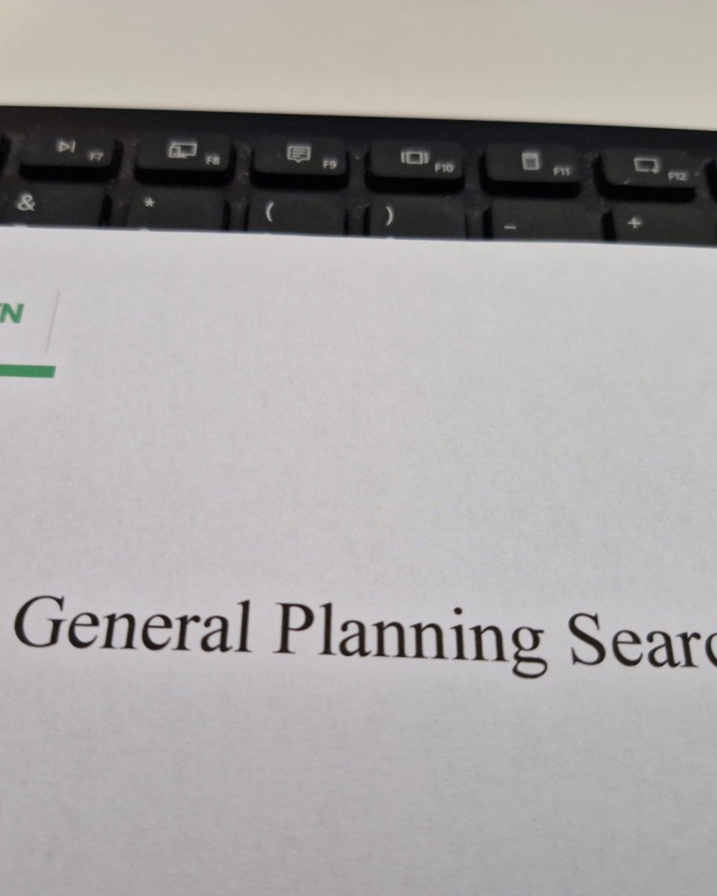 Close-up of a computer keyboard on a desk with part of a document visible that reads "General Planning Se".