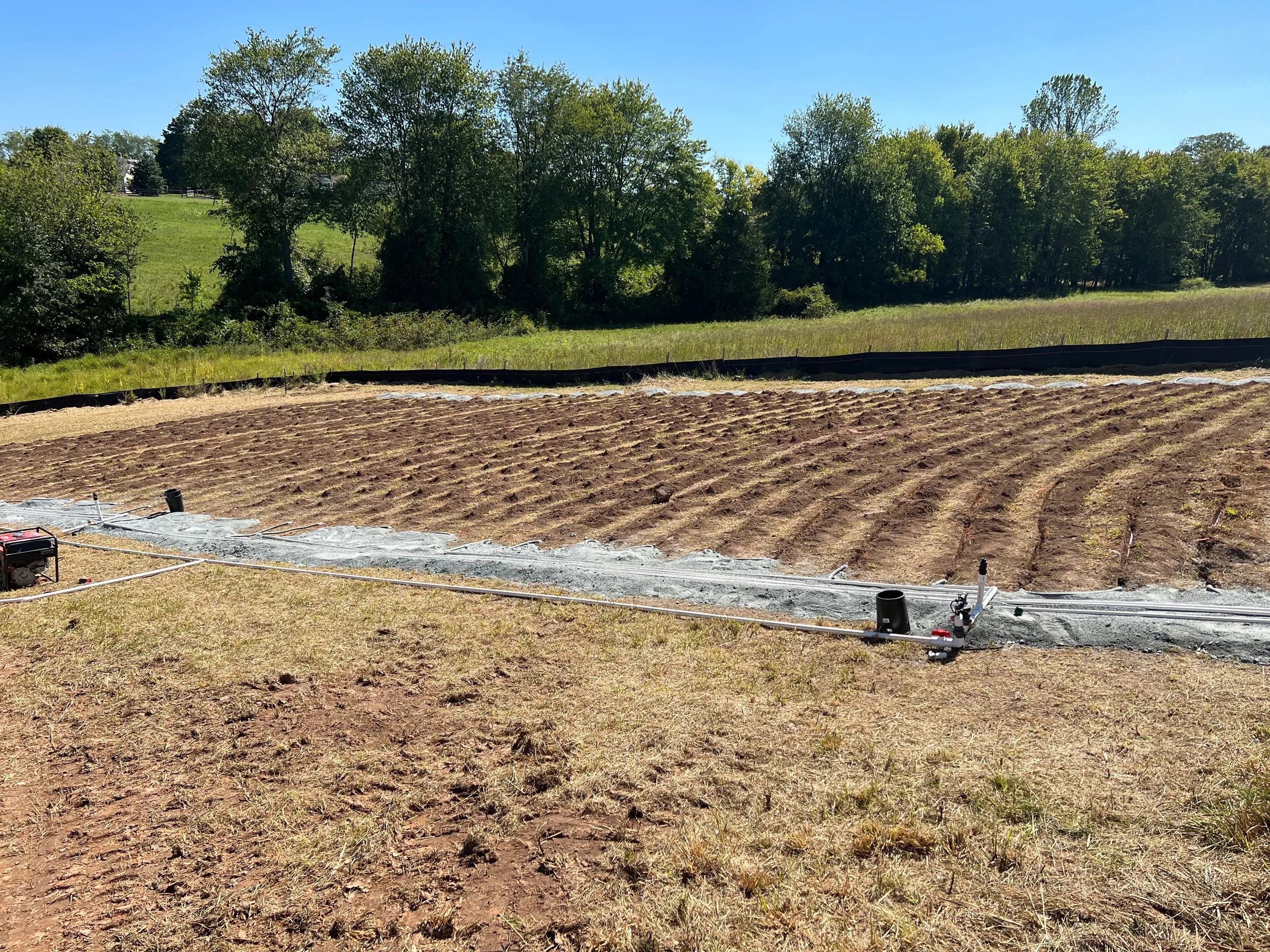 Graded drainfield with furrowed rows and supply manifold prepped for a drip dispersal septic system on a rural Northern Virginia property.