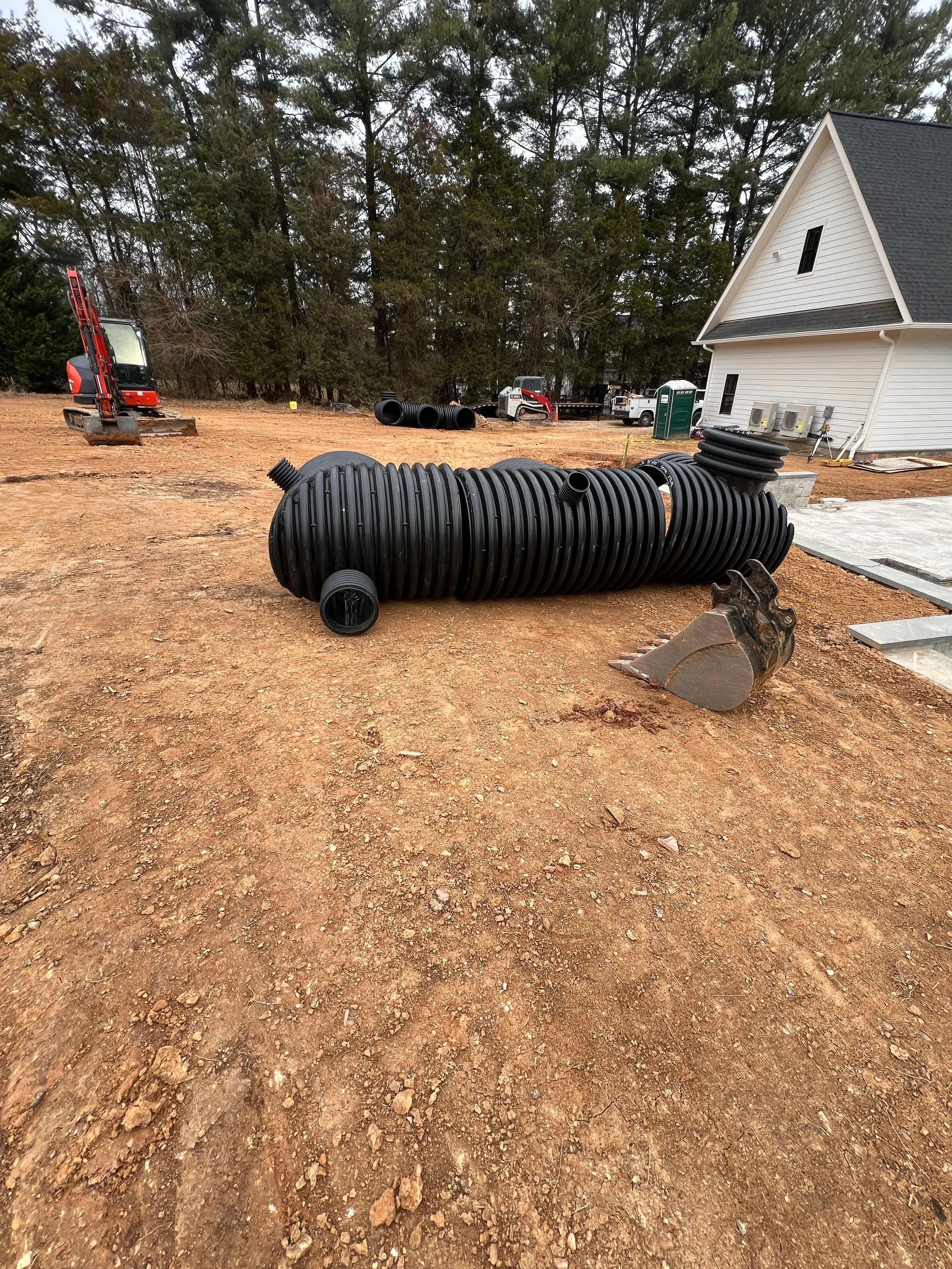 Large corrugated stormwater detention pipe staged on a graded residential site before underground BMP installation.