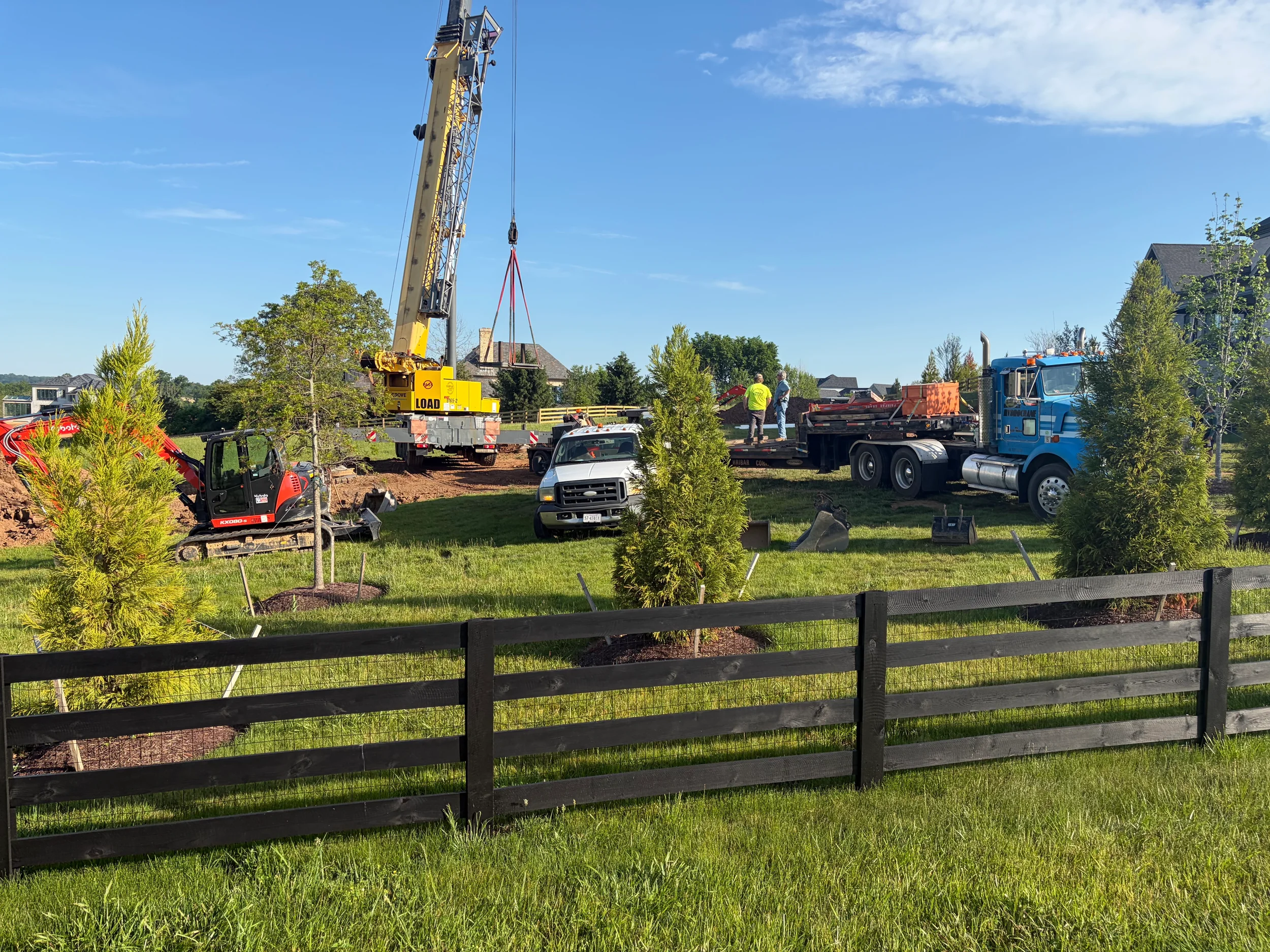 Crane and excavation crew setting a septic tank on a large residential lot, showing the heavy equipment used for septic and drainfield installation in Virginia.