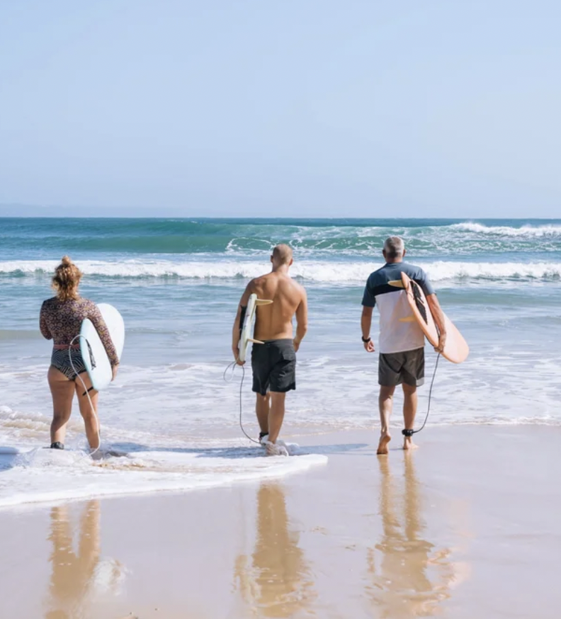 Beginner surfers heading out for a private small group lesson with surf instructor Chris Prewitt in Noosa