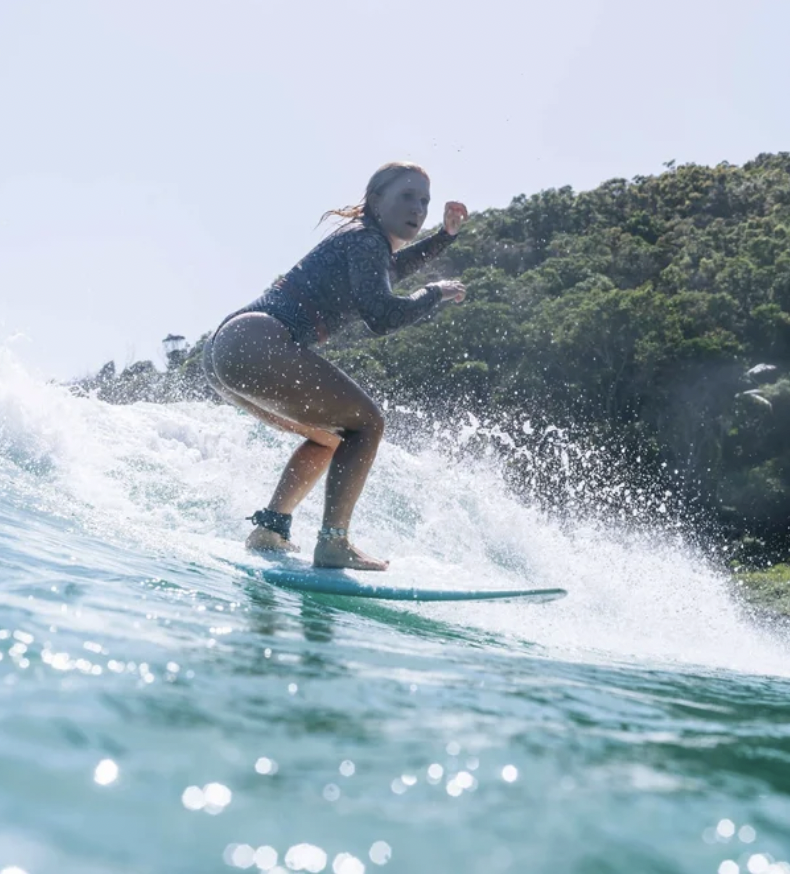 Beginner surfer catching a wave at Tea Tree Bay under the private surf instruction of Chris Prewitt in Noosa