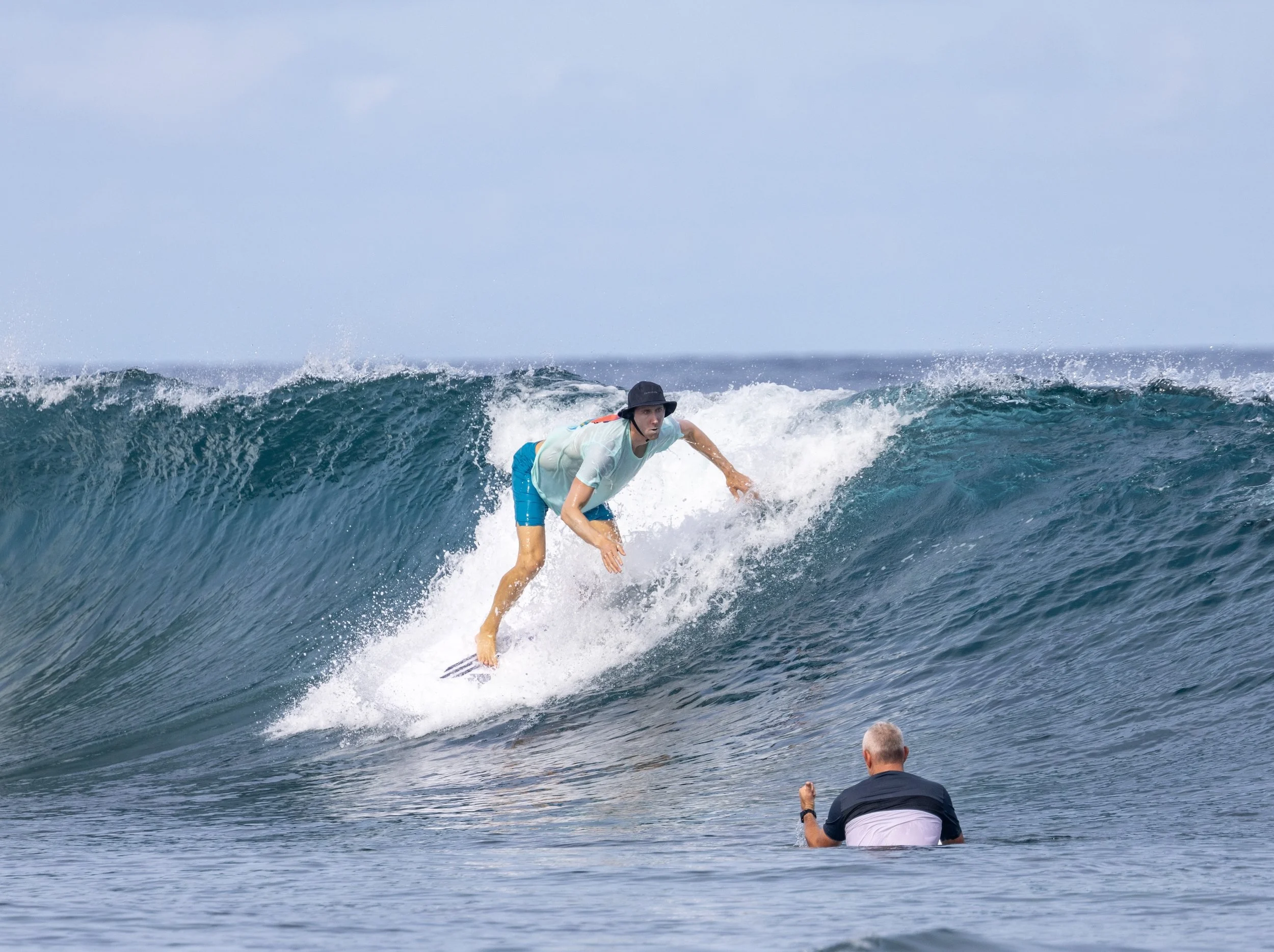 A beginner surfer receiving instruction and guidance from professional surf instructor Chris Prewitt whilst riding a wave