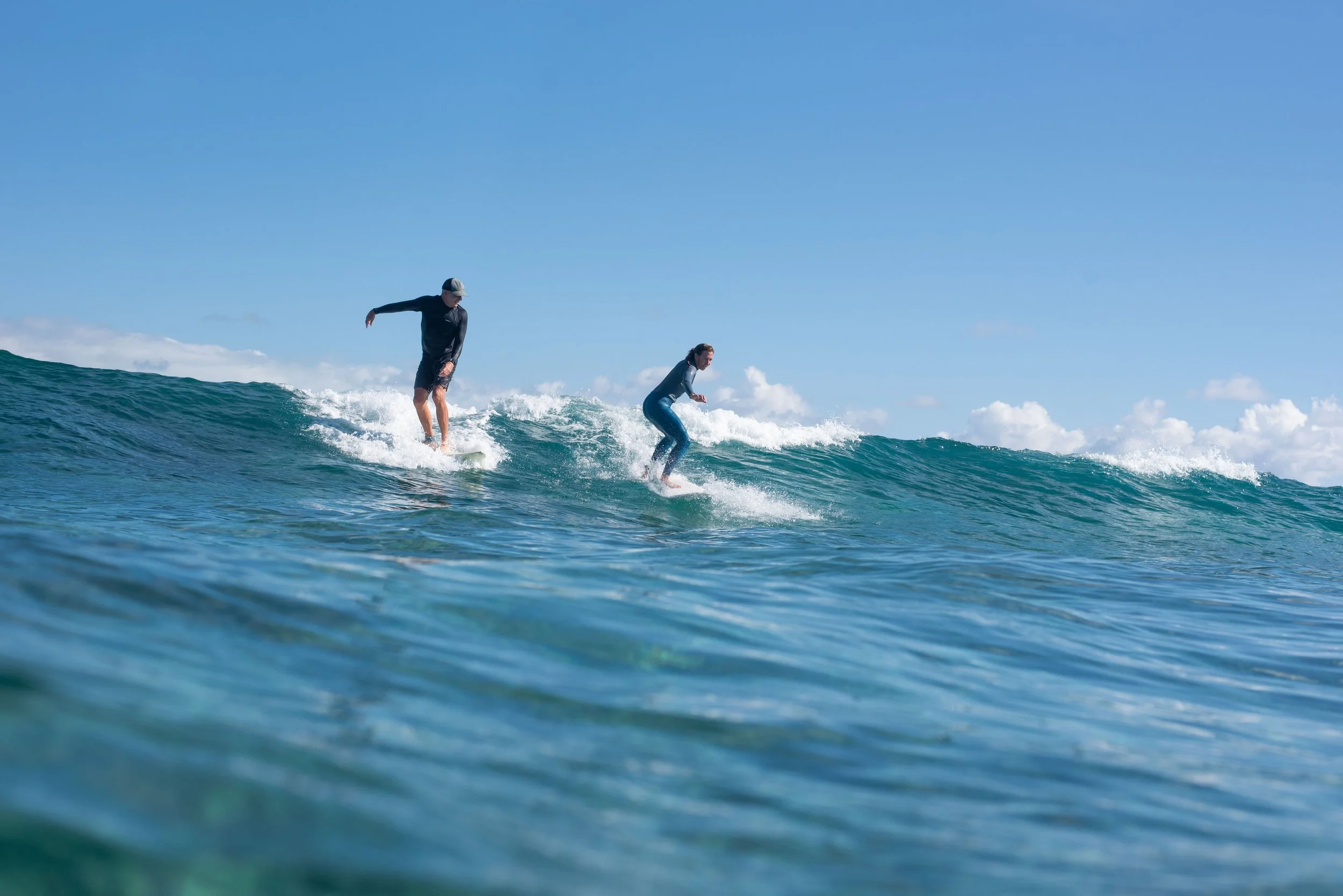 A beginner surfer riding a wave beside professional surf instructor Chris Prewitt