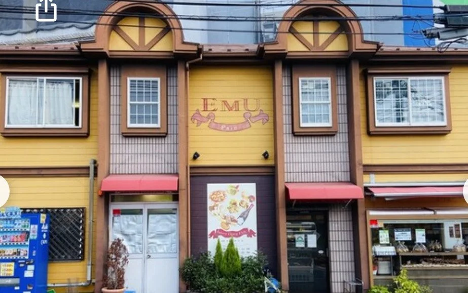 黄色と茶色の外壁の建物、看板に「EMU」と描かれている。