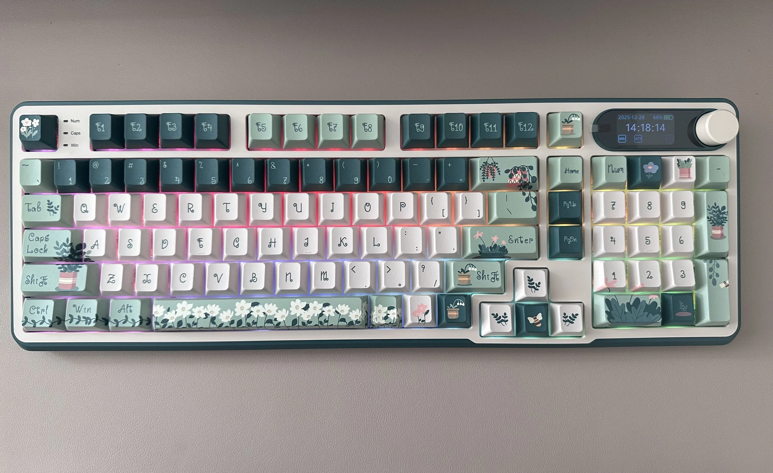 A colorful mechanical keyboard with pastel-themed keycaps featuring floral and plant designs, including flowers, potted plants, and greenery, illuminated with pink, purple, and green backlighting.