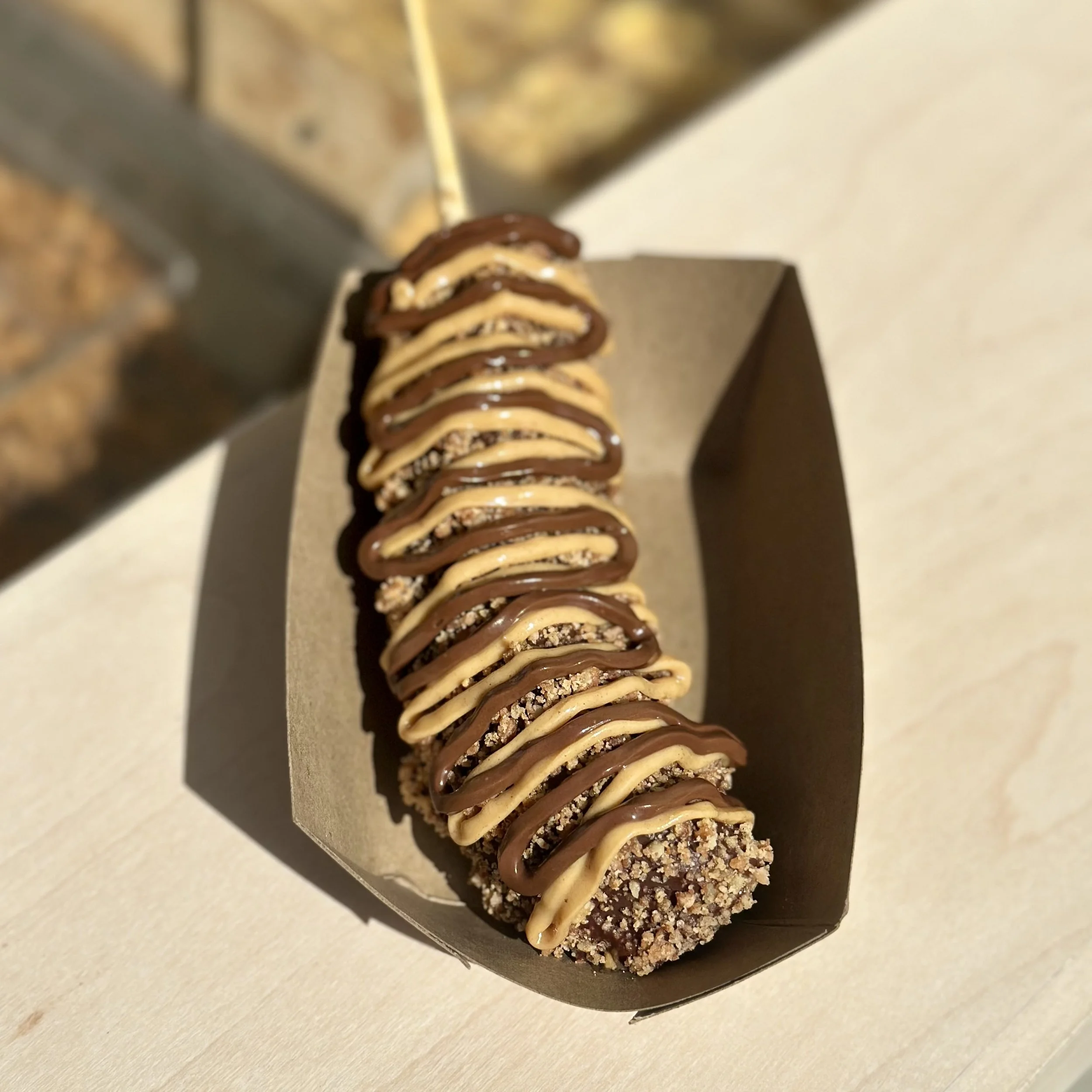 A frozen chocolate dipped banana. This is called the Go Nuts. It has butter toffee peanuts and Nutella and peanut butter drizzles.