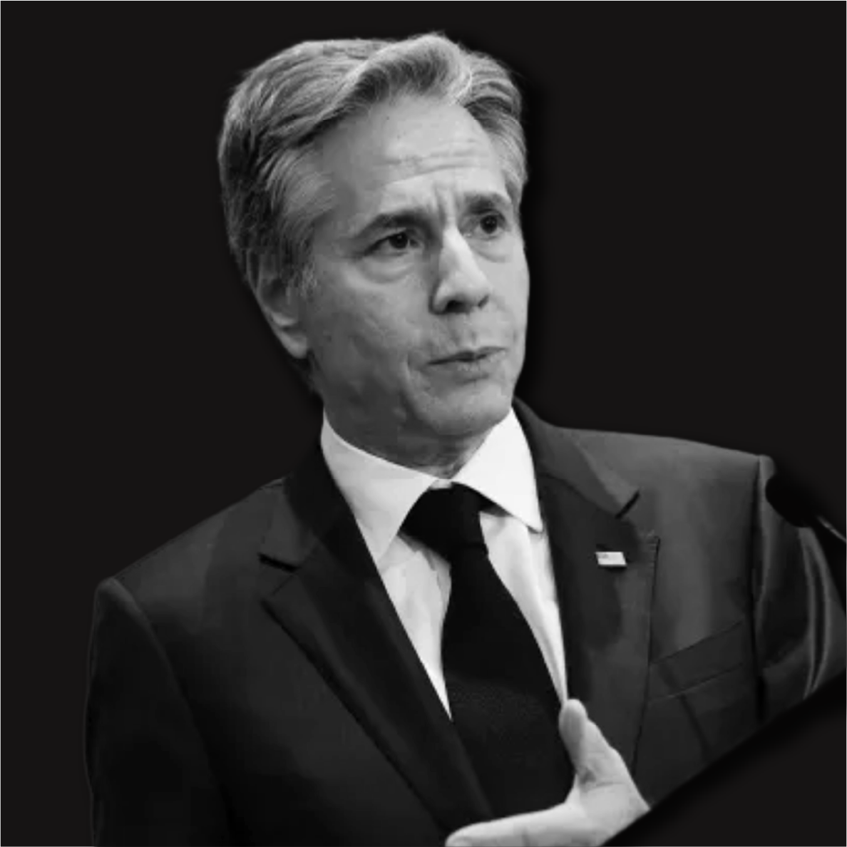 Black and white photo of a man in a suit speaking at a podium.
