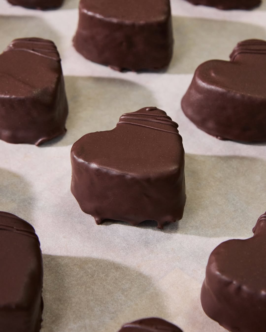 Heart-shaped chocolate-covered candies on parchment paper.