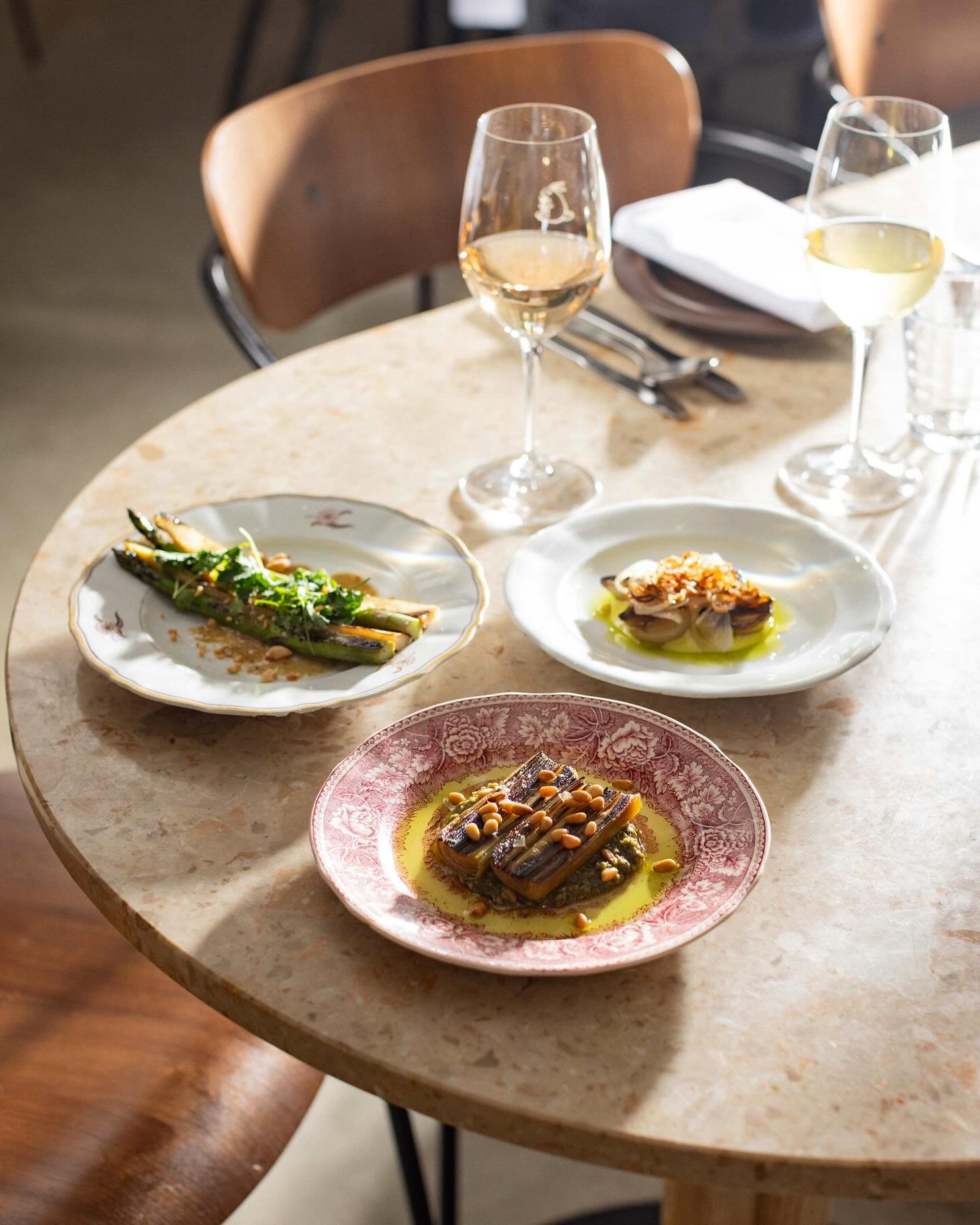 A marble table with various plated appetizers and two glasses of white wine.