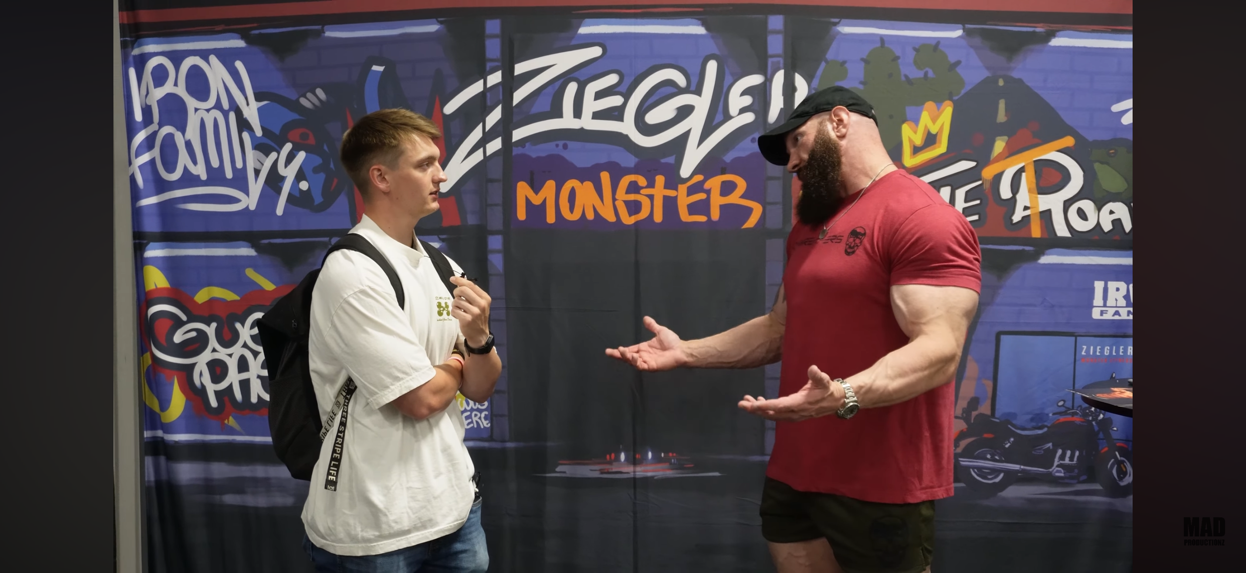 Two men are having a conversation against a graffiti-style background with words like 'Monster' and 'Family' and images of a dragon and motorcycles.