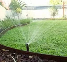 A sprinkler watering a lush green lawn in a backyard.